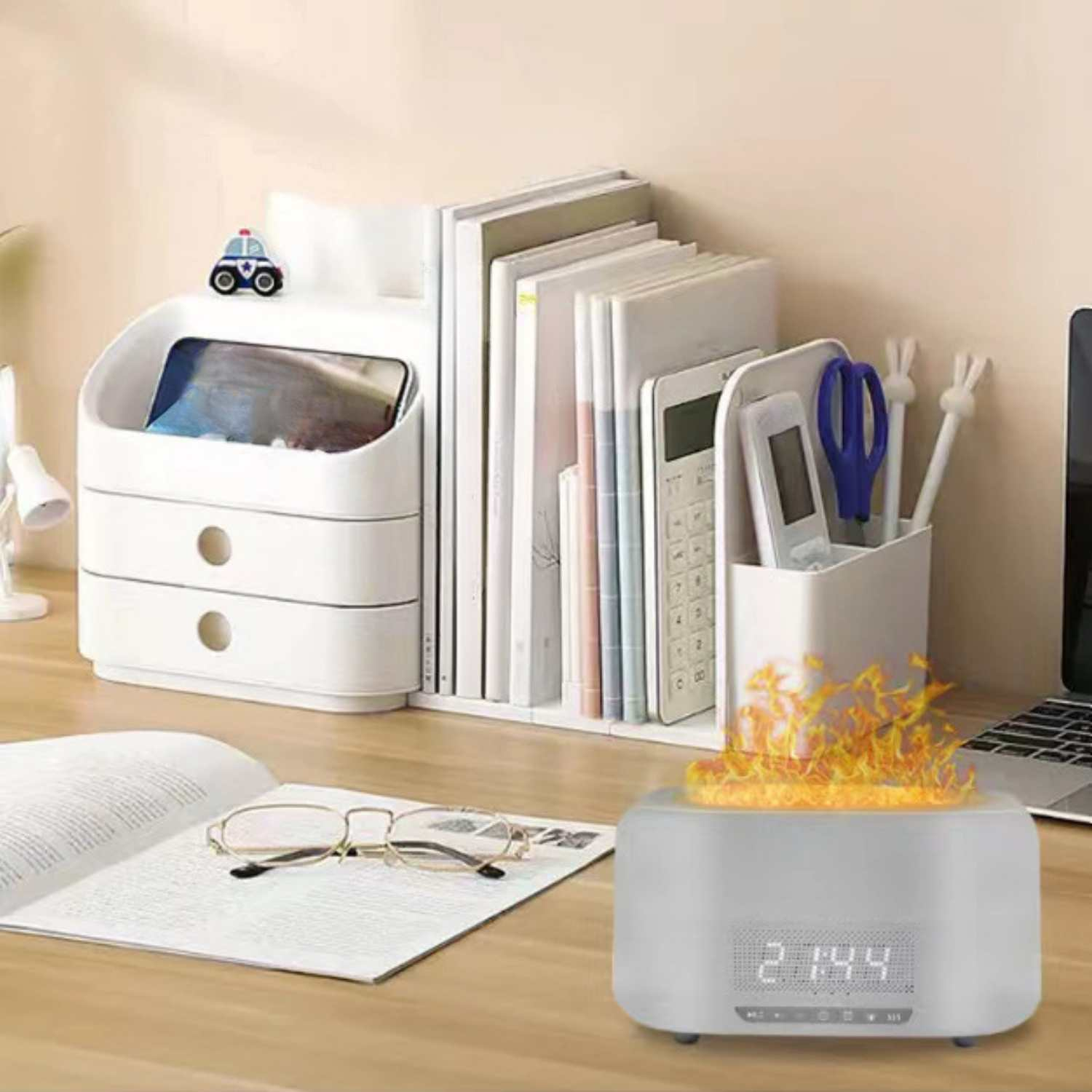 Ein Schreibtisch mit Büchern, einem Organizer, einer Brille und einem Wecker mit Flammen-Effekt.