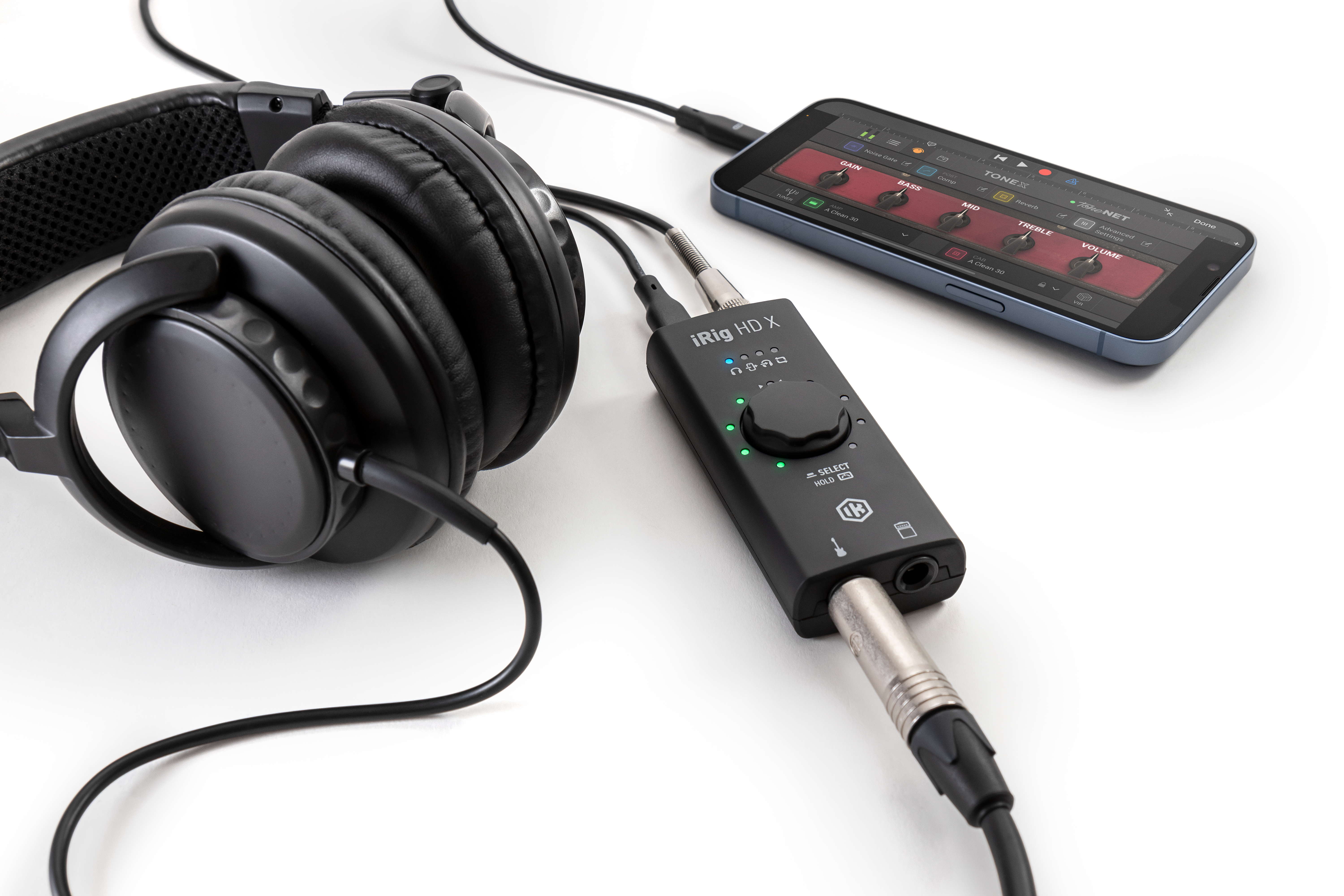 Schwarze Kopfhörer, ein iRig HD X und ein Smartphone mit Audio-App auf weißem Hintergrund.