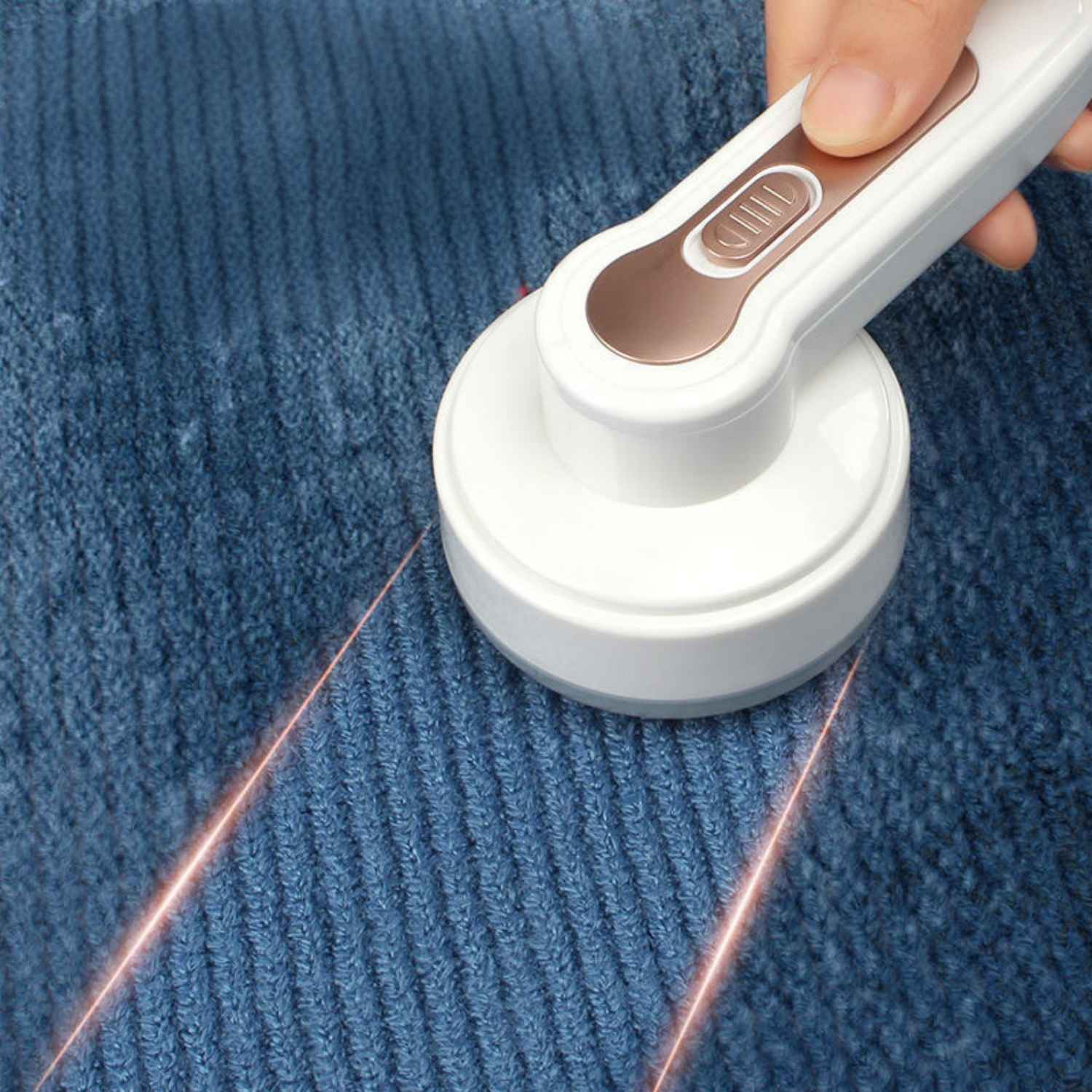 Ein weißer Fusselentferner wird über einen blauen Strickstoff geführt.