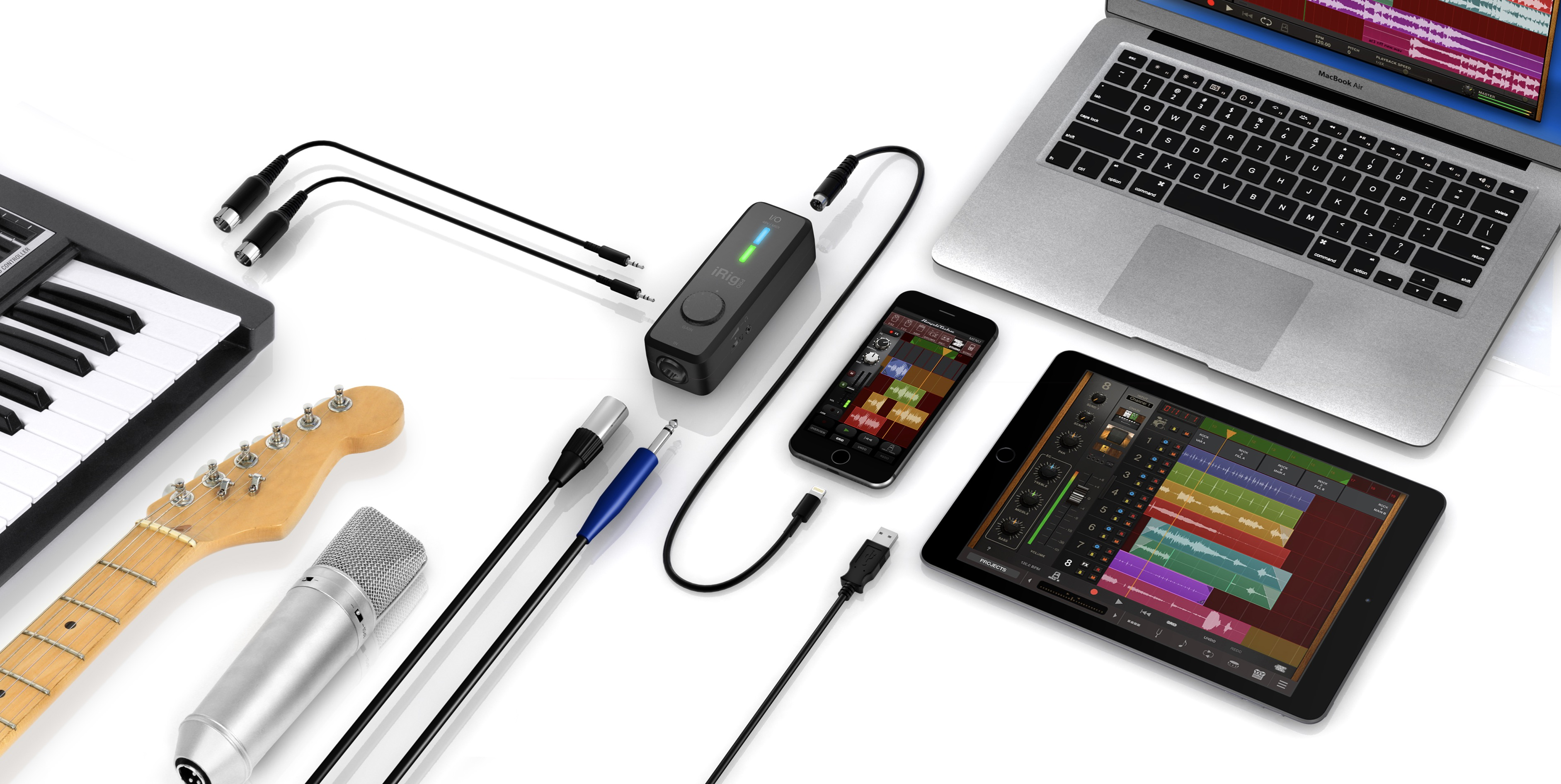Musikproduktion-Setup mit Laptop, Tablet, Smartphone, Gitarre, Mikrofon, Keyboards und Kabeln.