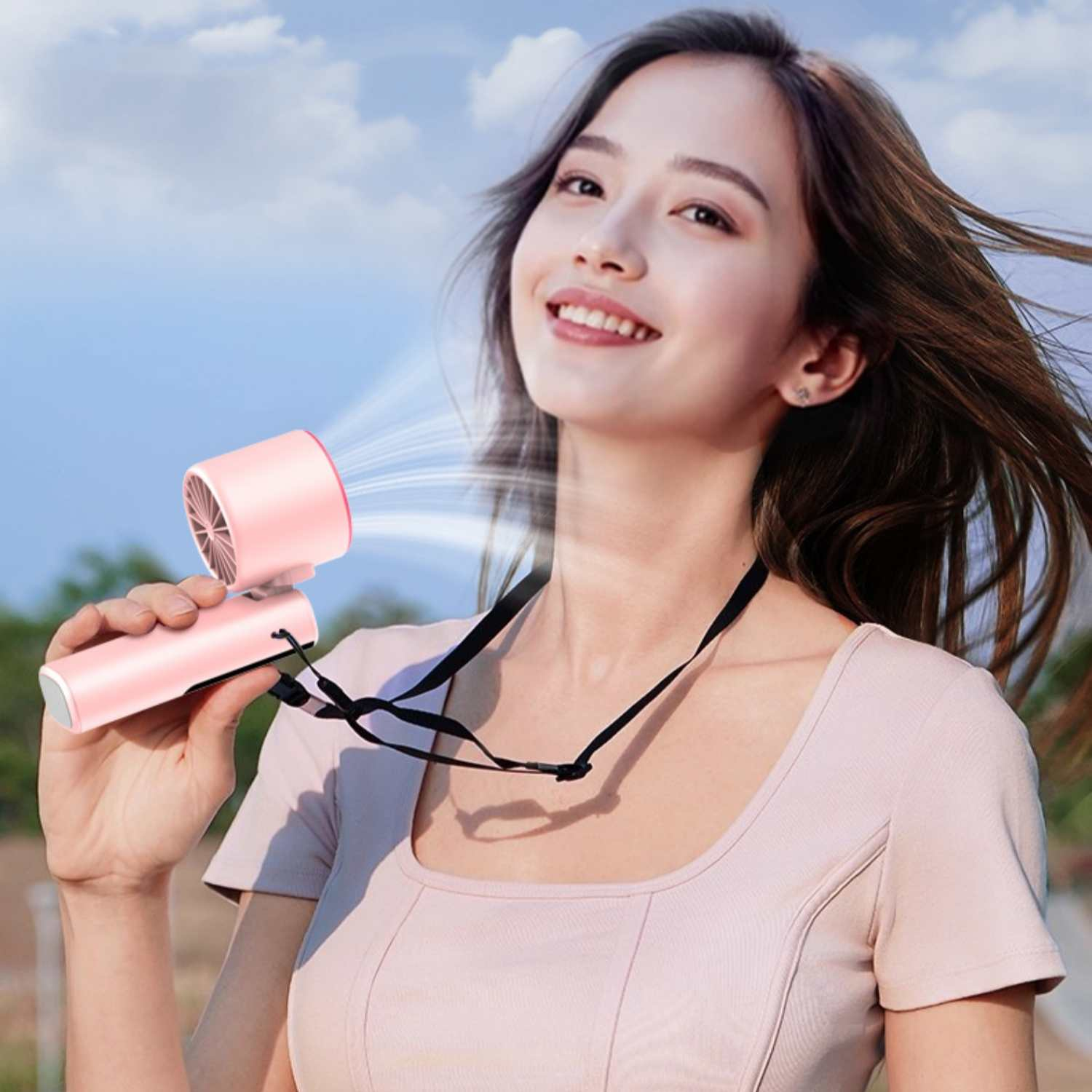 Eine Frau hält einen rosa Ventilator, der Luft bläst, im Freien.