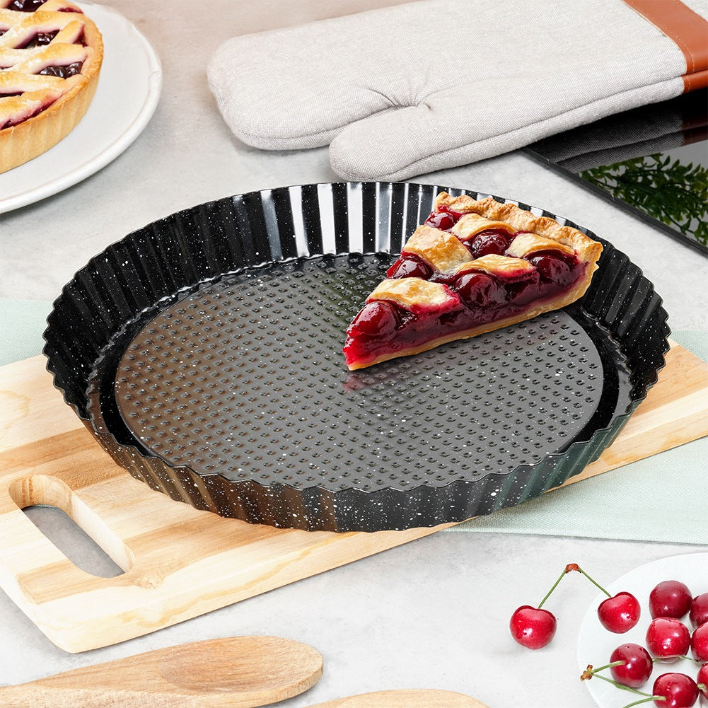 Una rebanada de tarta de cereza en un molde negro acanalado sobre tabla de madera.