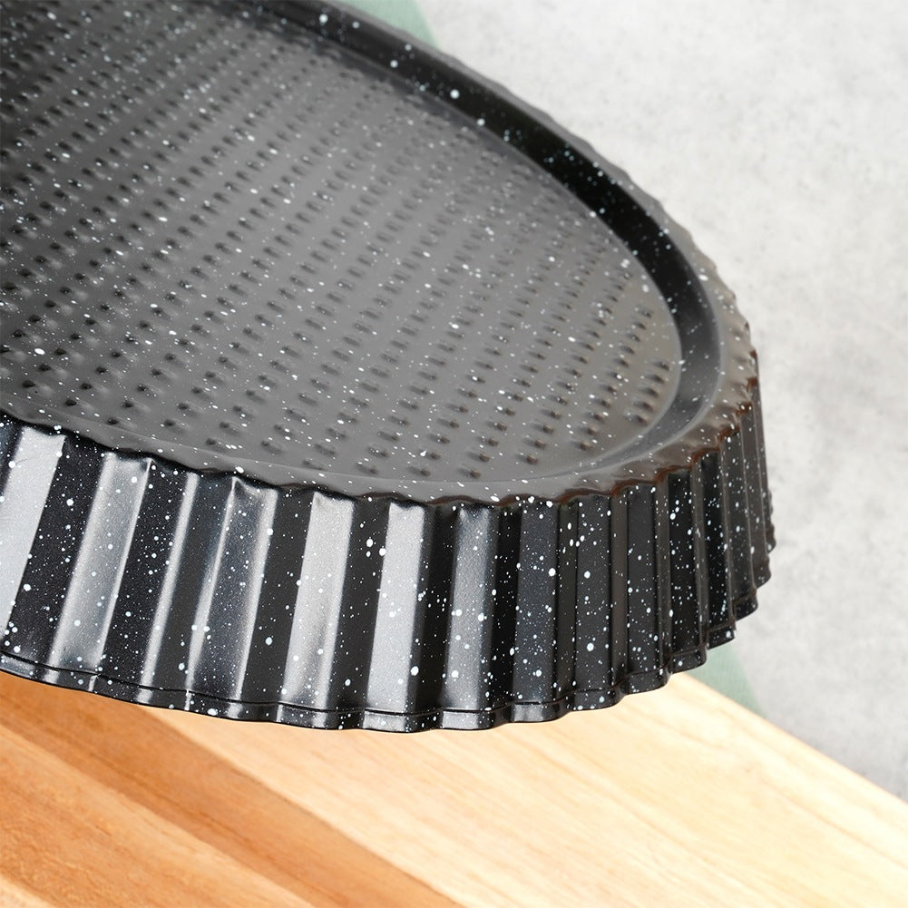 Un molde para tarta negro con motas blancas descansa sobre una superficie de madera.
