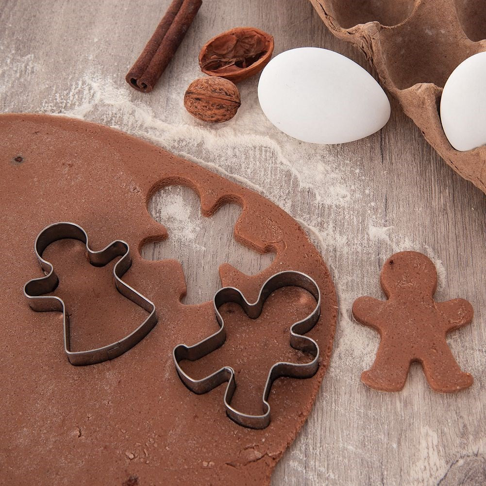 Masa de chocolate con cortadores, nueces, canela y huevos sobre fondo de madera.