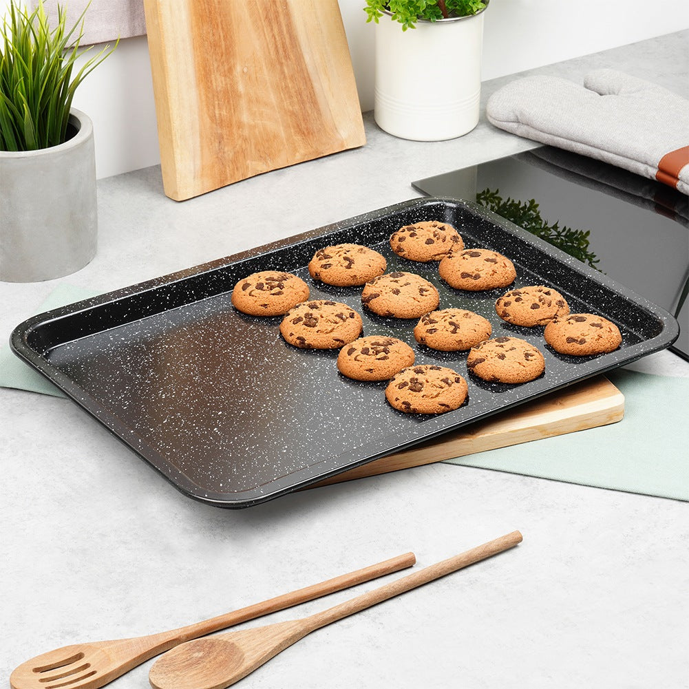 Una bandeja para hornear llena de galletas con chispas de chocolate y cucharas de madera.
