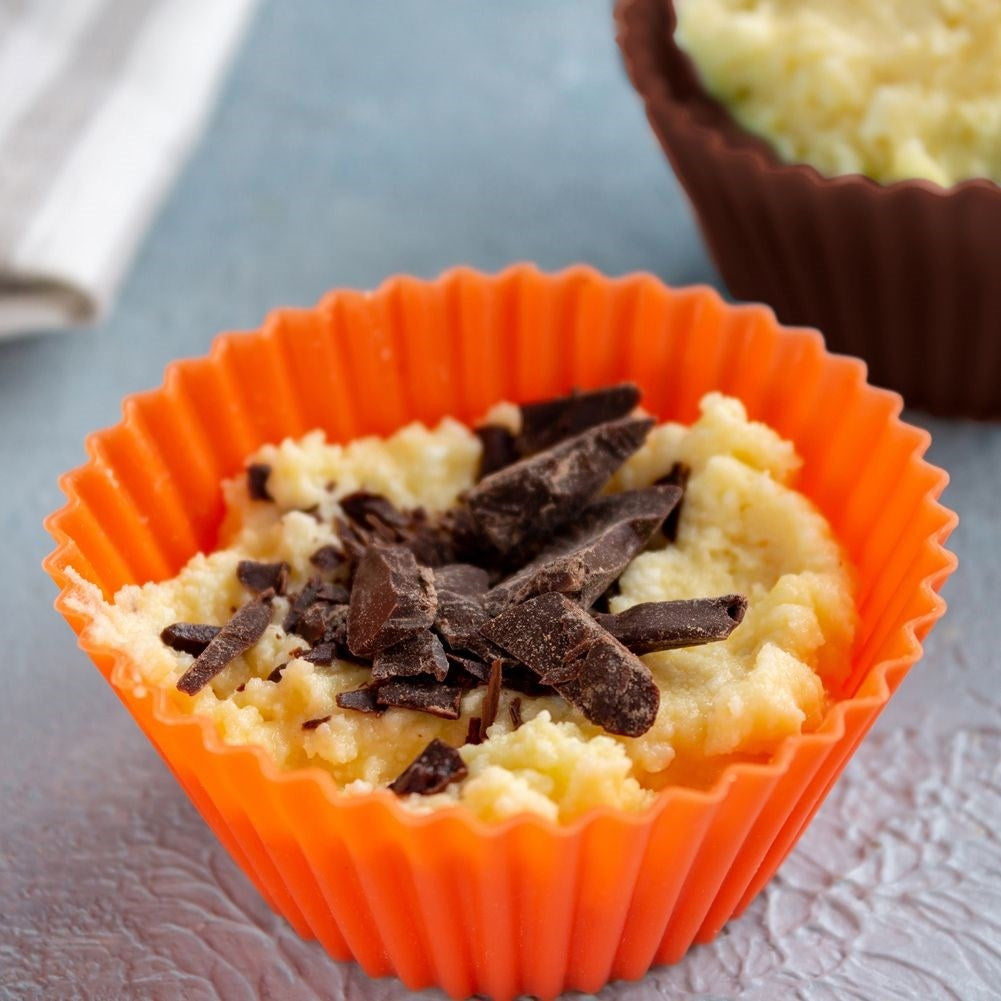 Un capacillo naranja relleno de masa clara y trozos de chocolate oscuro.