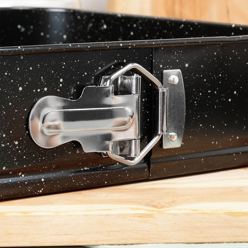 Un molde rectangular negro salpicado con un cierre plateado sobre madera.