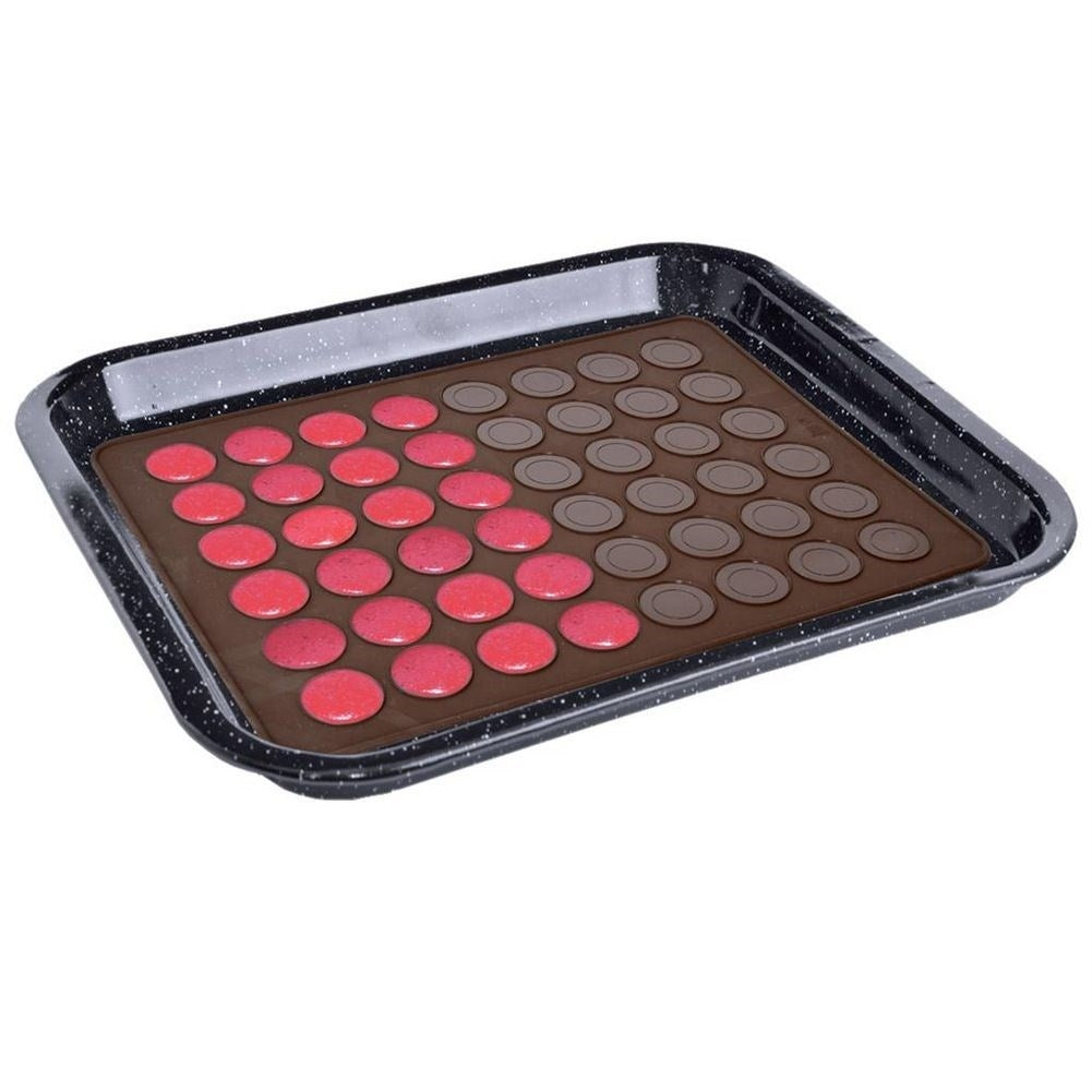 Bandeja de horno con dos filas de porciones redondas de masa de macaron, una roja, una marrón.