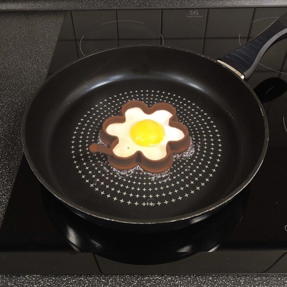 Un huevo frito con forma de flor se cocina en una sartén sobre una estufa.