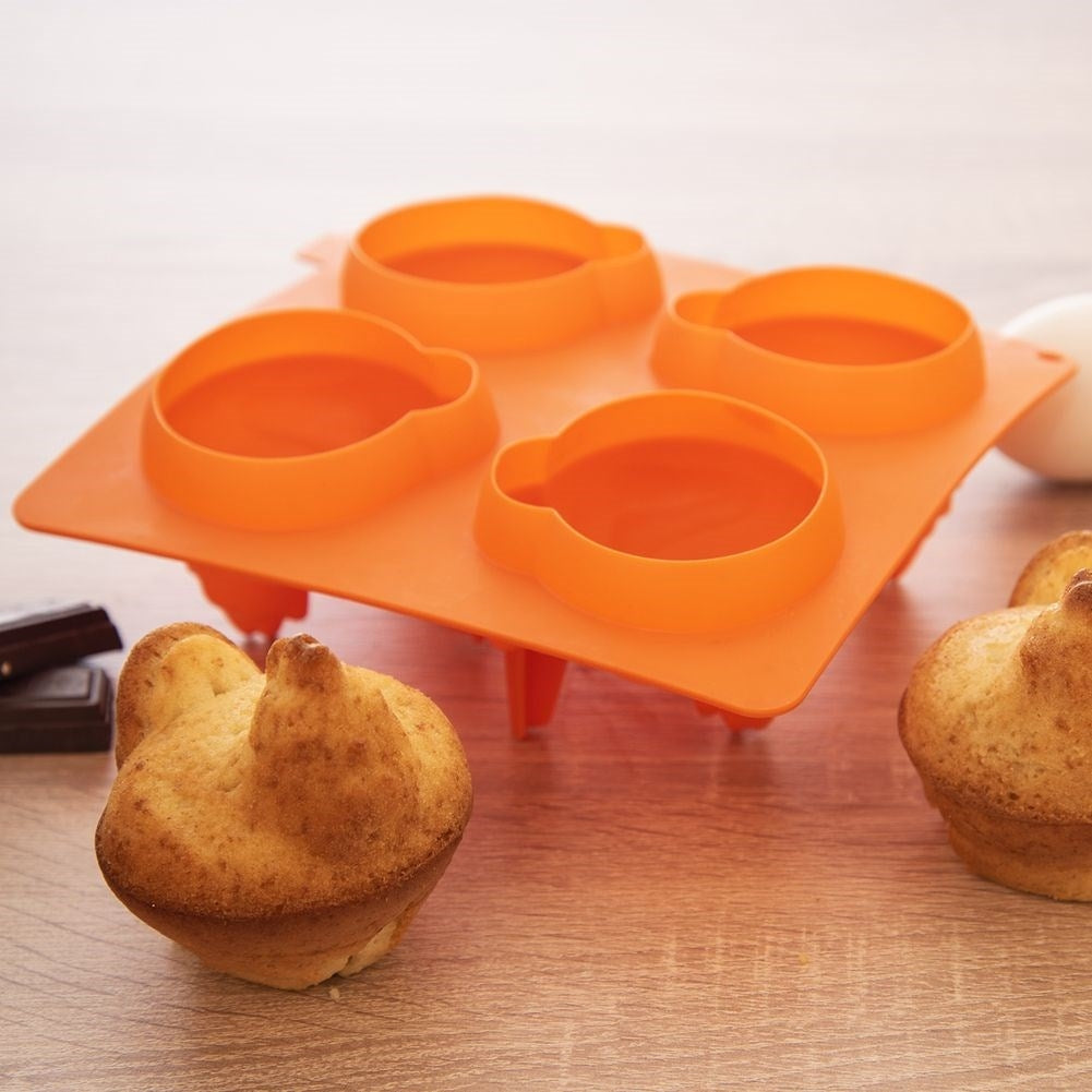 Un molde para hornear naranja con cuatro cavidades redondas sobre una mesa de madera.