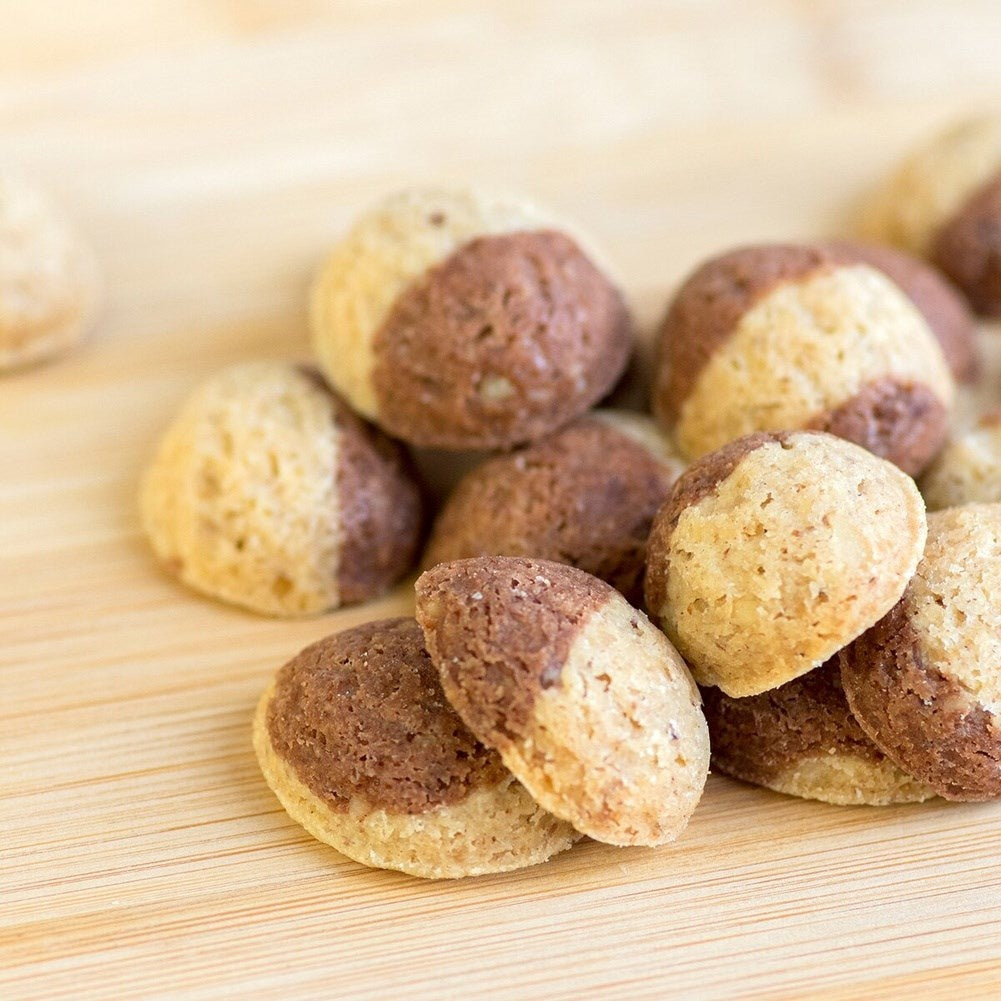 Galletas bicolor, mitad claras y mitad marrones oscuras, sobre una tabla de madera.