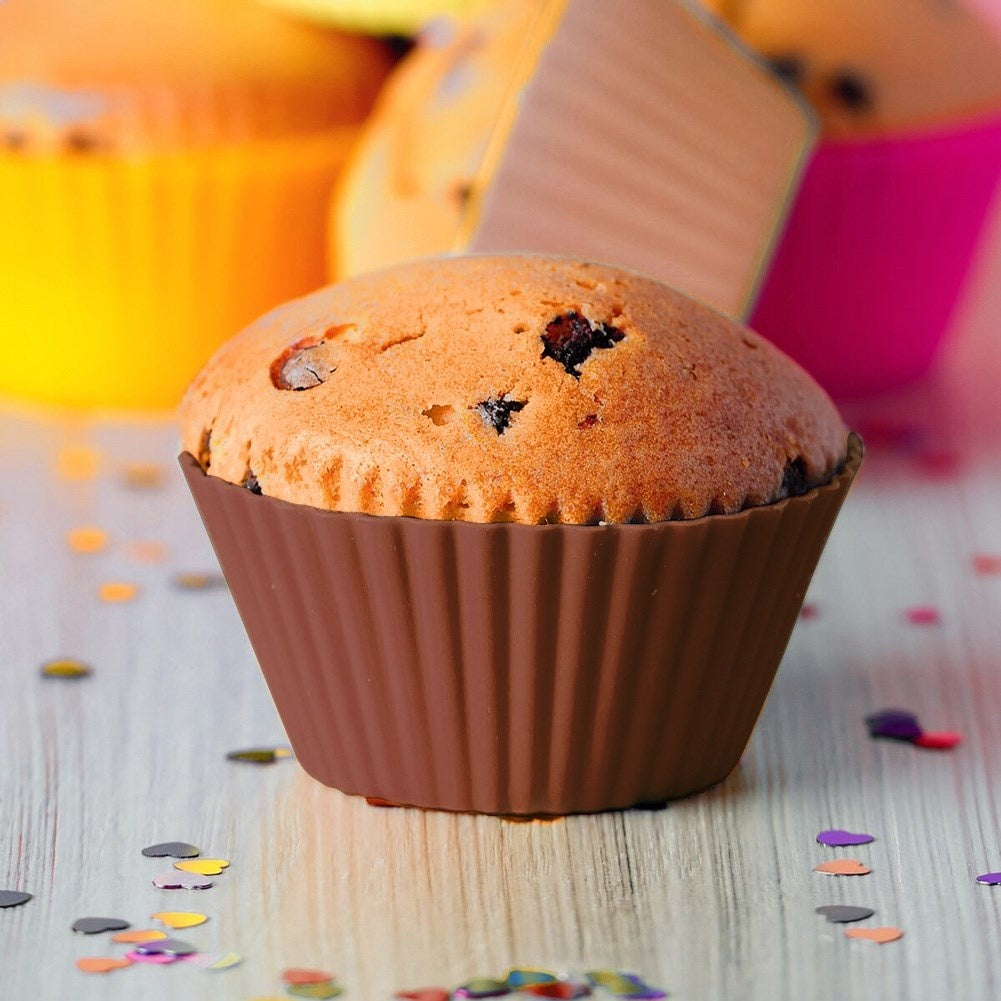 Un muffin en envoltorio marrón sobre mesa de madera con confeti.