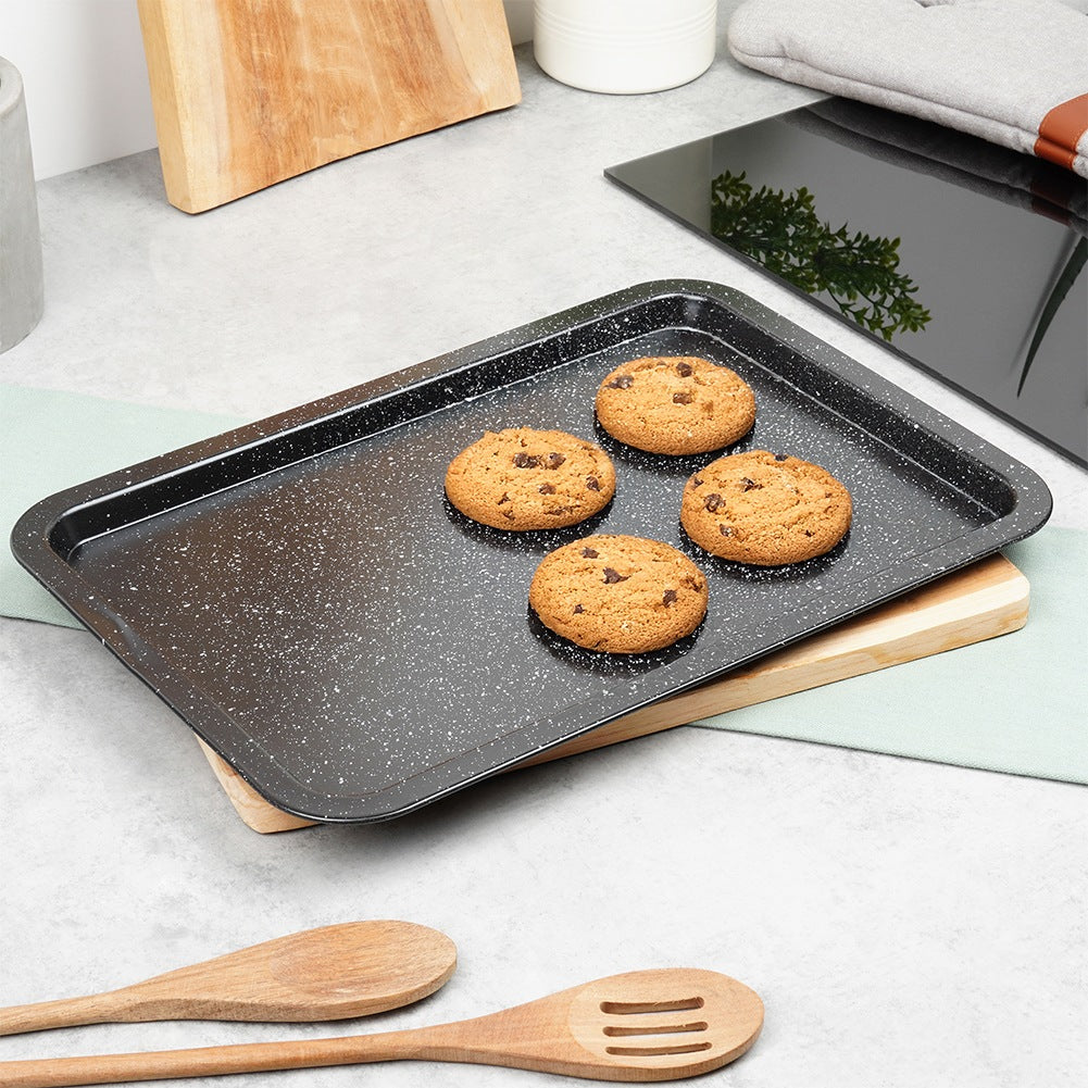 Cuatro galletas con chispas de chocolate en una bandeja para hornear negra.