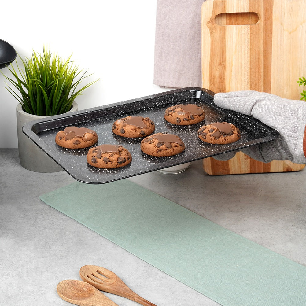 Una bandeja de horno con seis galletas de chispas de chocolate es sostenida. Un guante de cocina protege la mano.