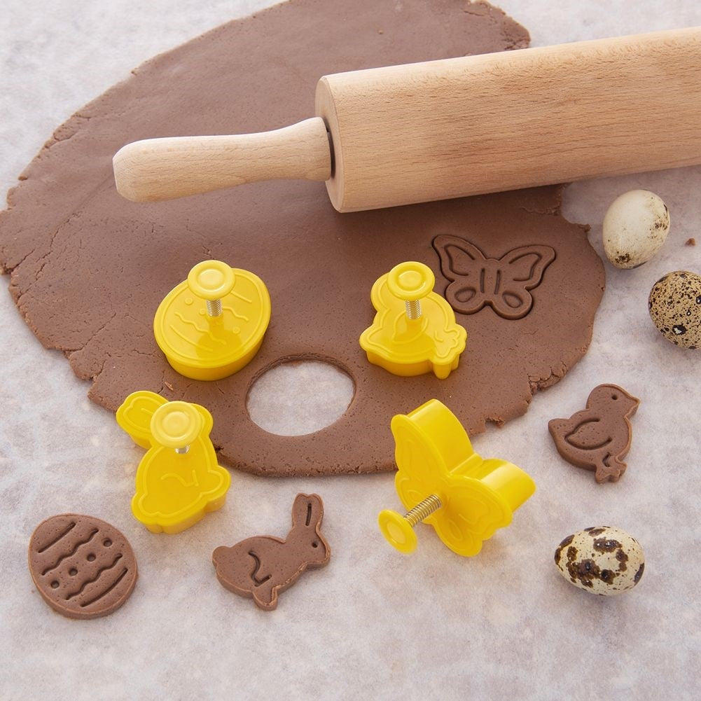 Masa de galleta marrón con cortadores en forma de conejitos, mariposas, pollitos y huevos.