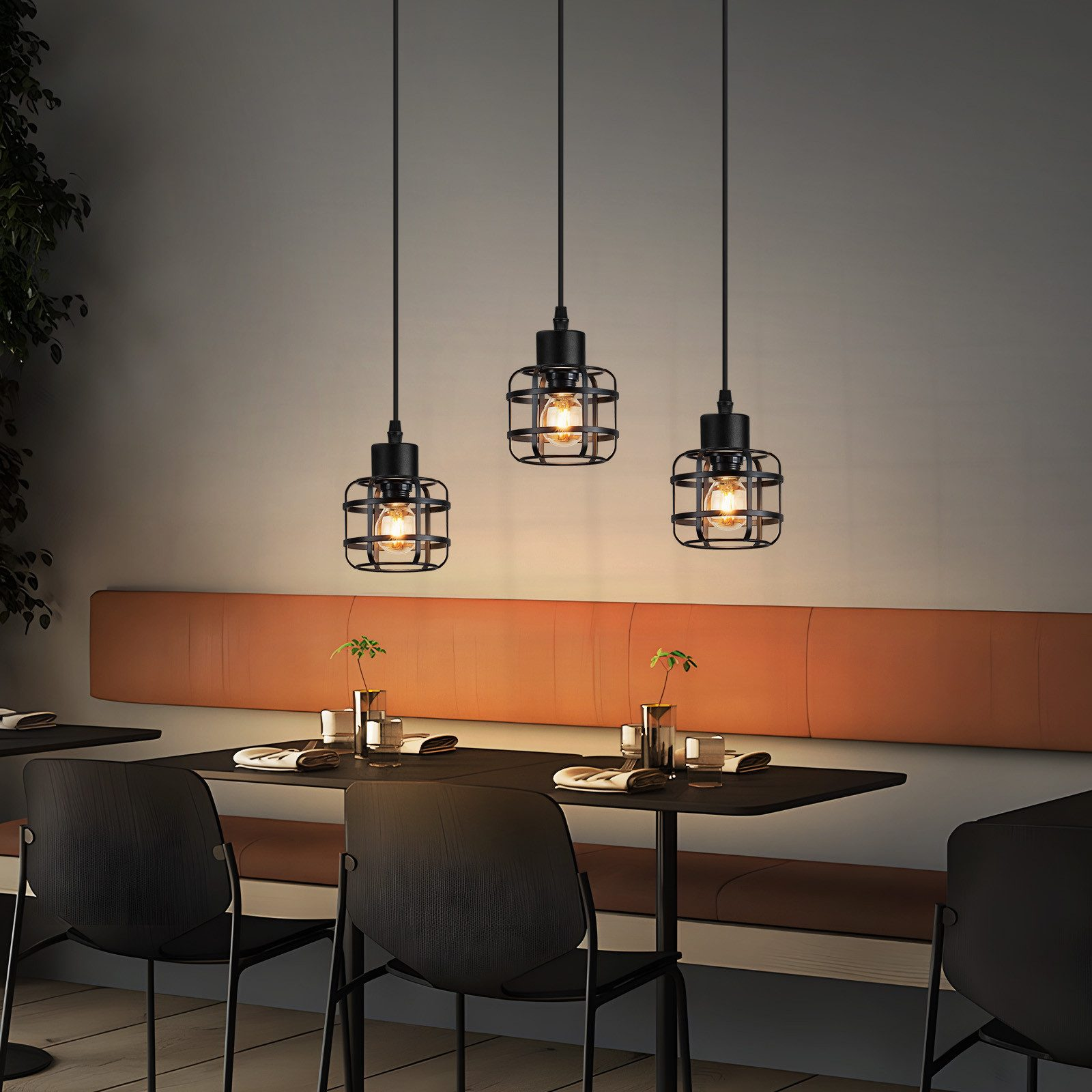 Drei schwarze Pendelleuchten mit Käfig-Design über einem Tisch.