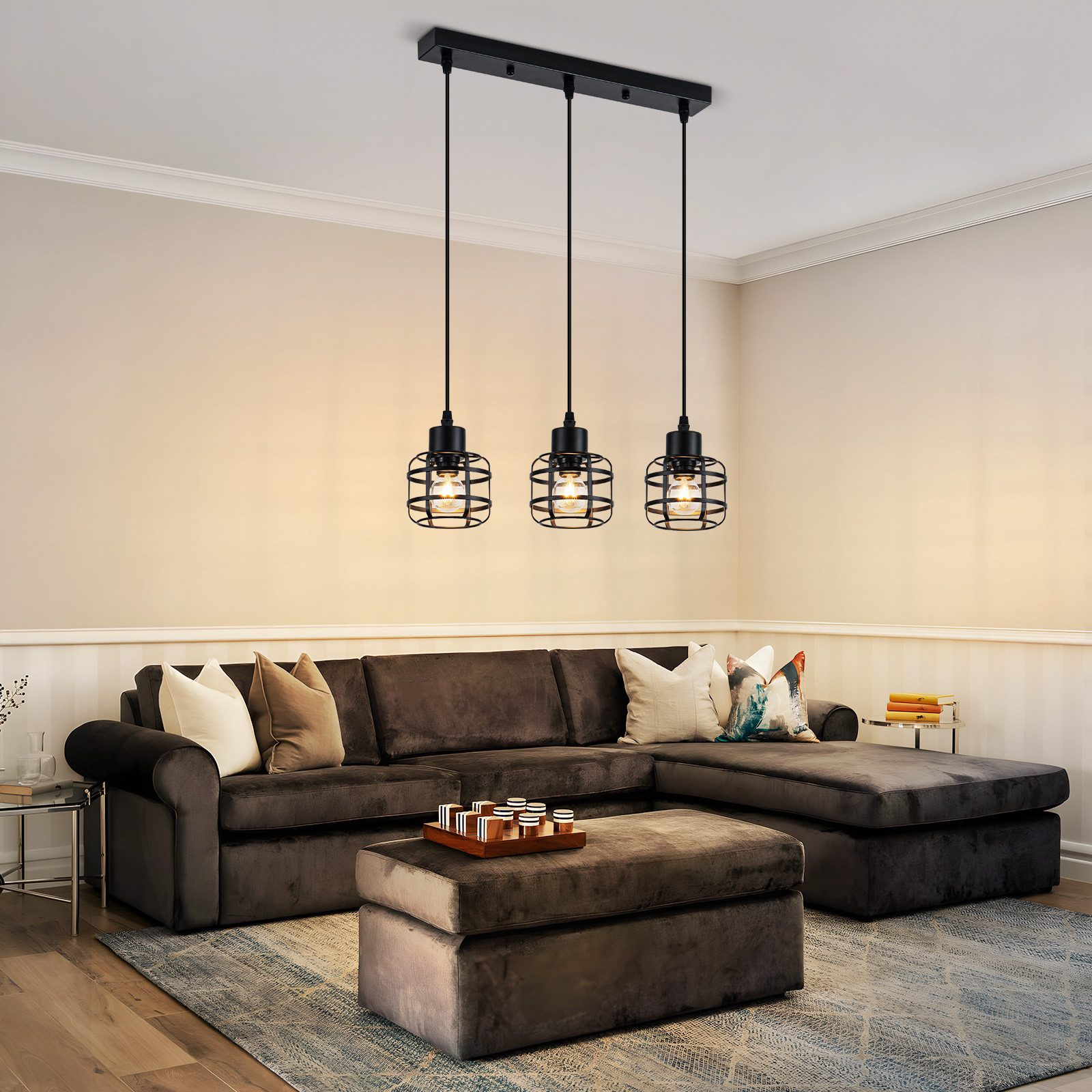 Drei schwarze Pendelleuchten mit Käfigschirm hängen über einem dunklen Sofa.