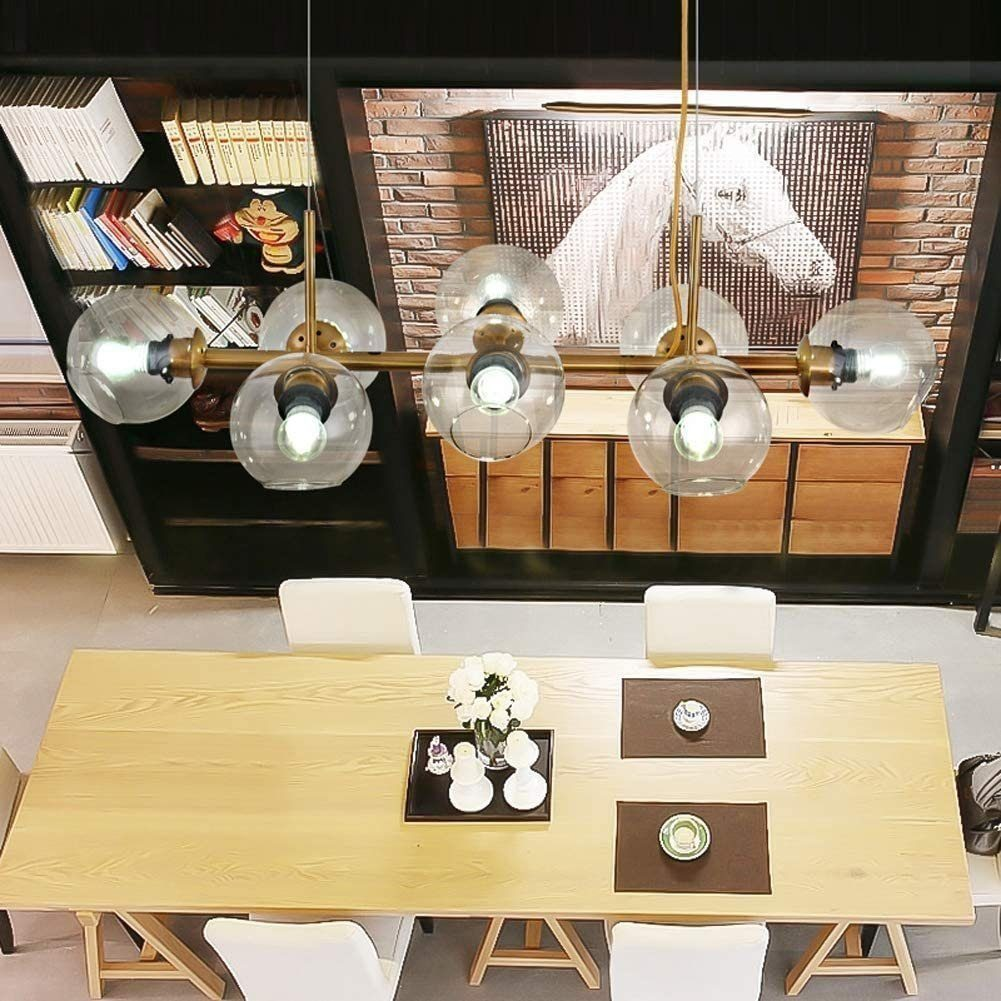 Tavolo in legno con sedie bianche, cesto con fiori e lampadario con sfere di vetro.