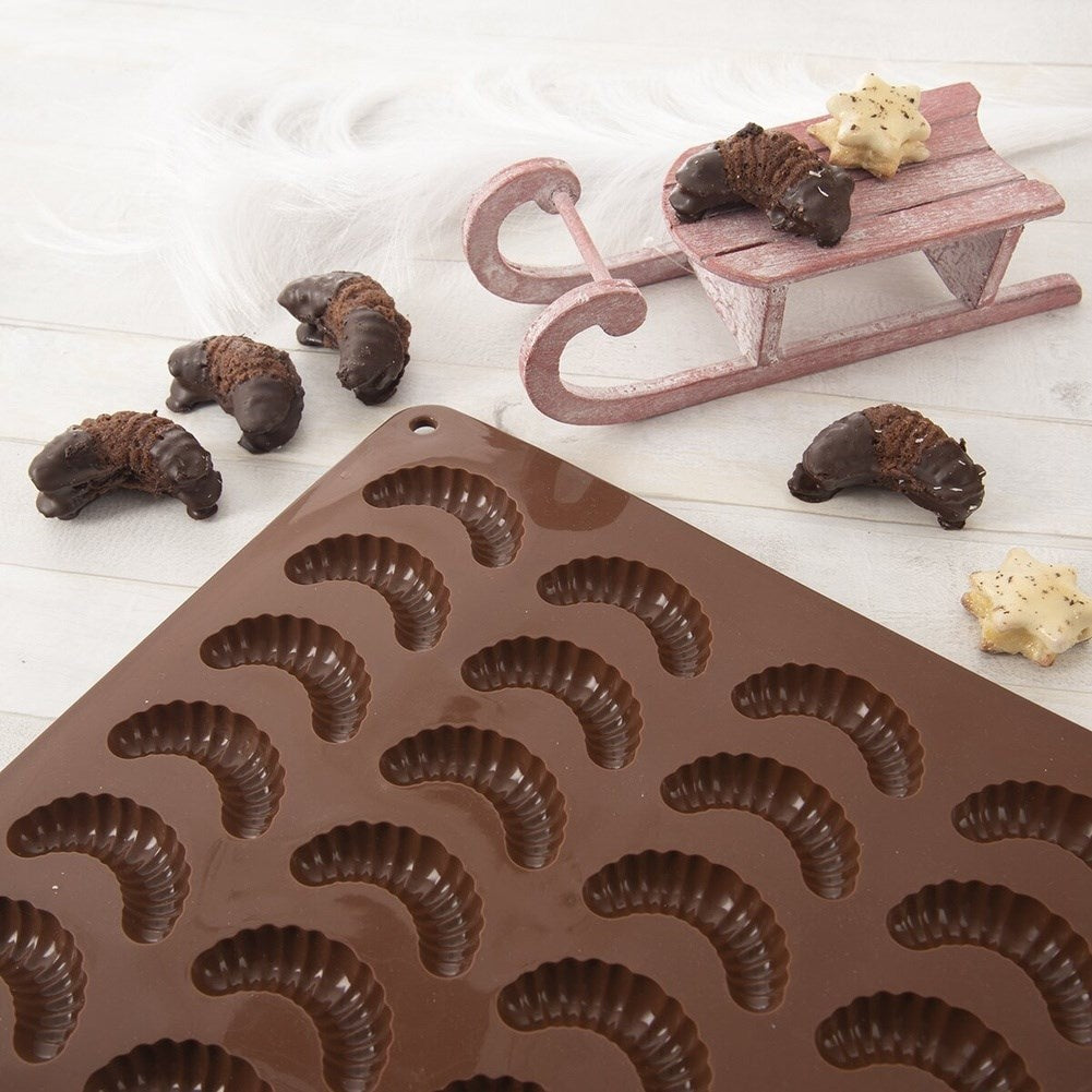 Galletas de chocolate en un trineo y en un molde sobre fondo claro.