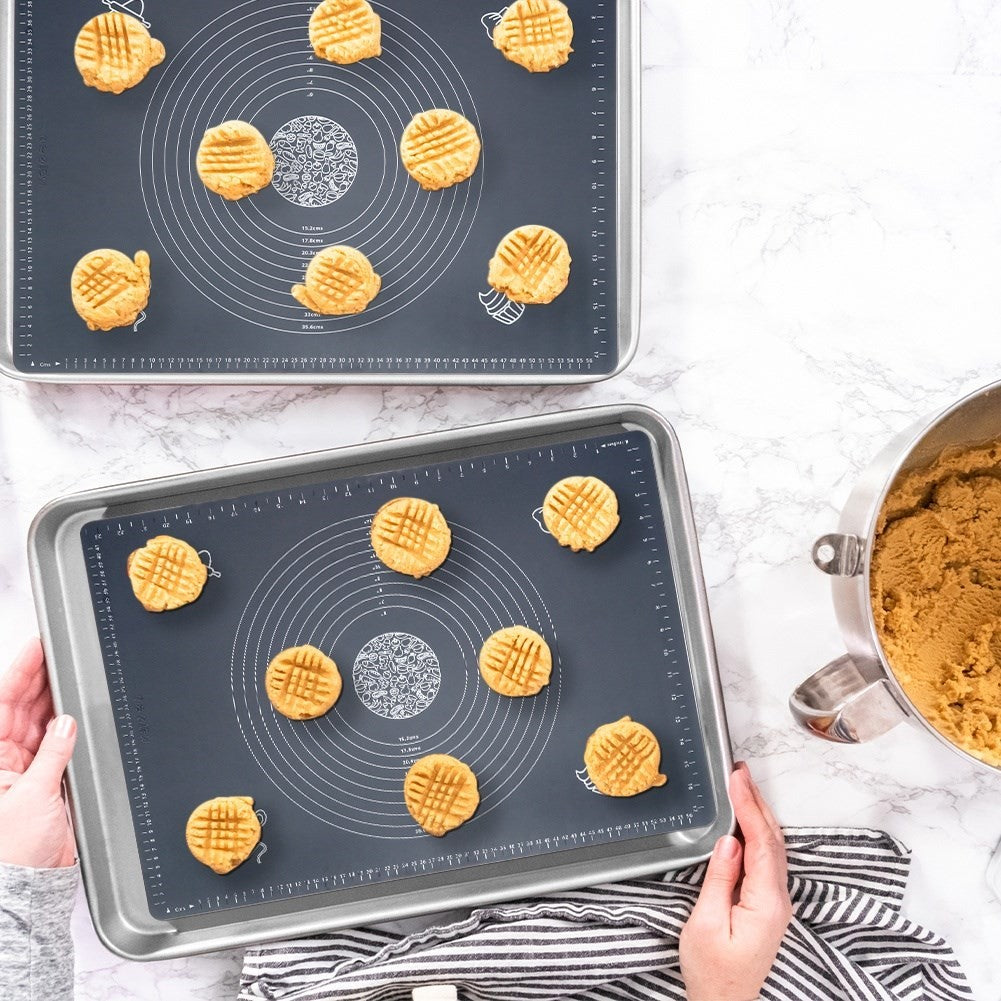 Dos bandejas de horno con galletas sin hornear, al lado un bol con masa.