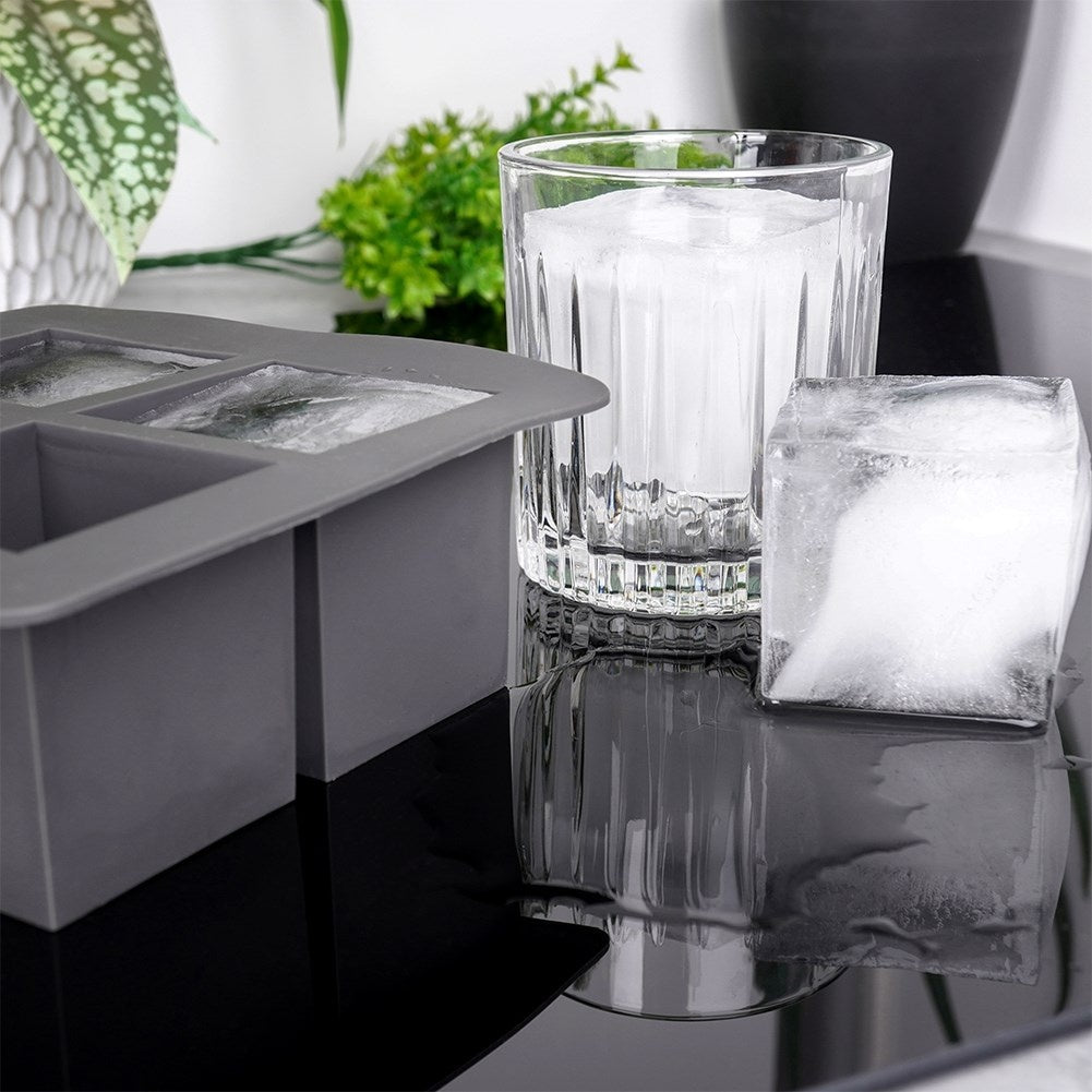 Una cubitera de silicona gris, un vaso con hielo y un cubito de hielo.