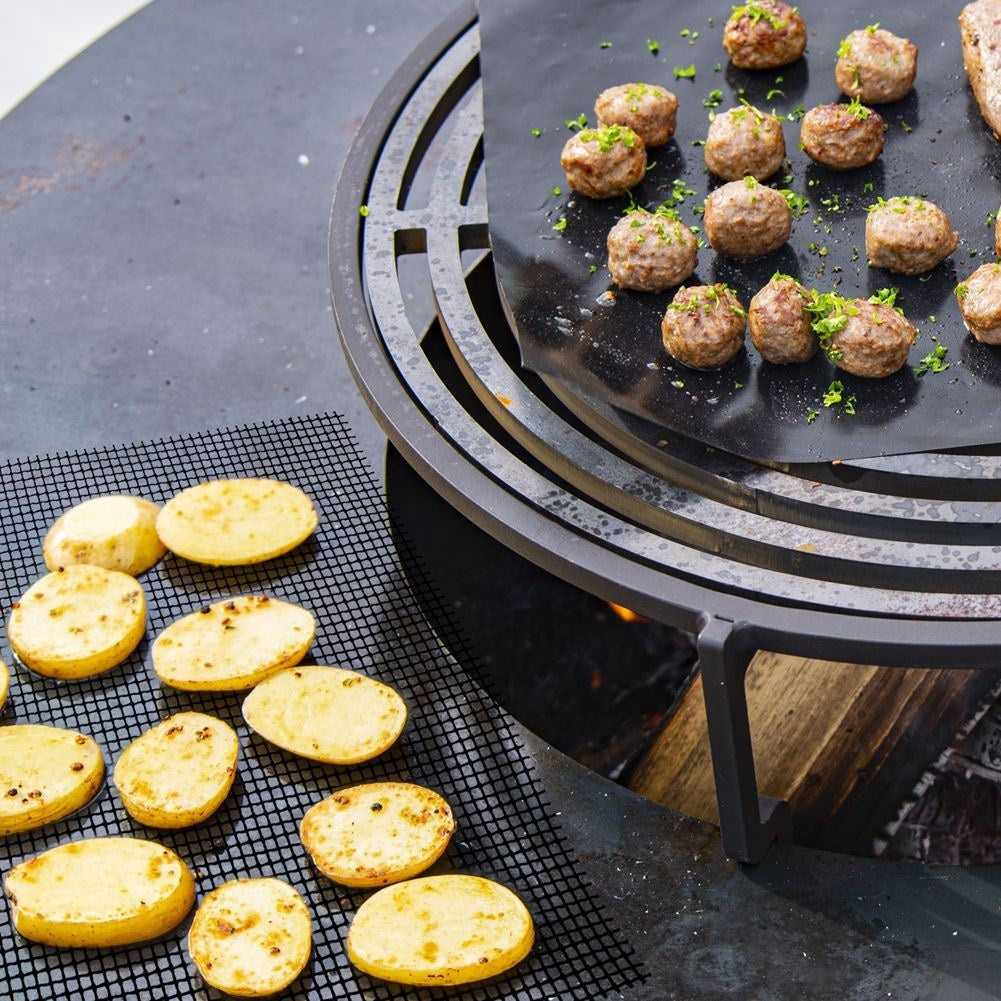 Albóndigas y rodajas de patata se cocinan en una parrilla.