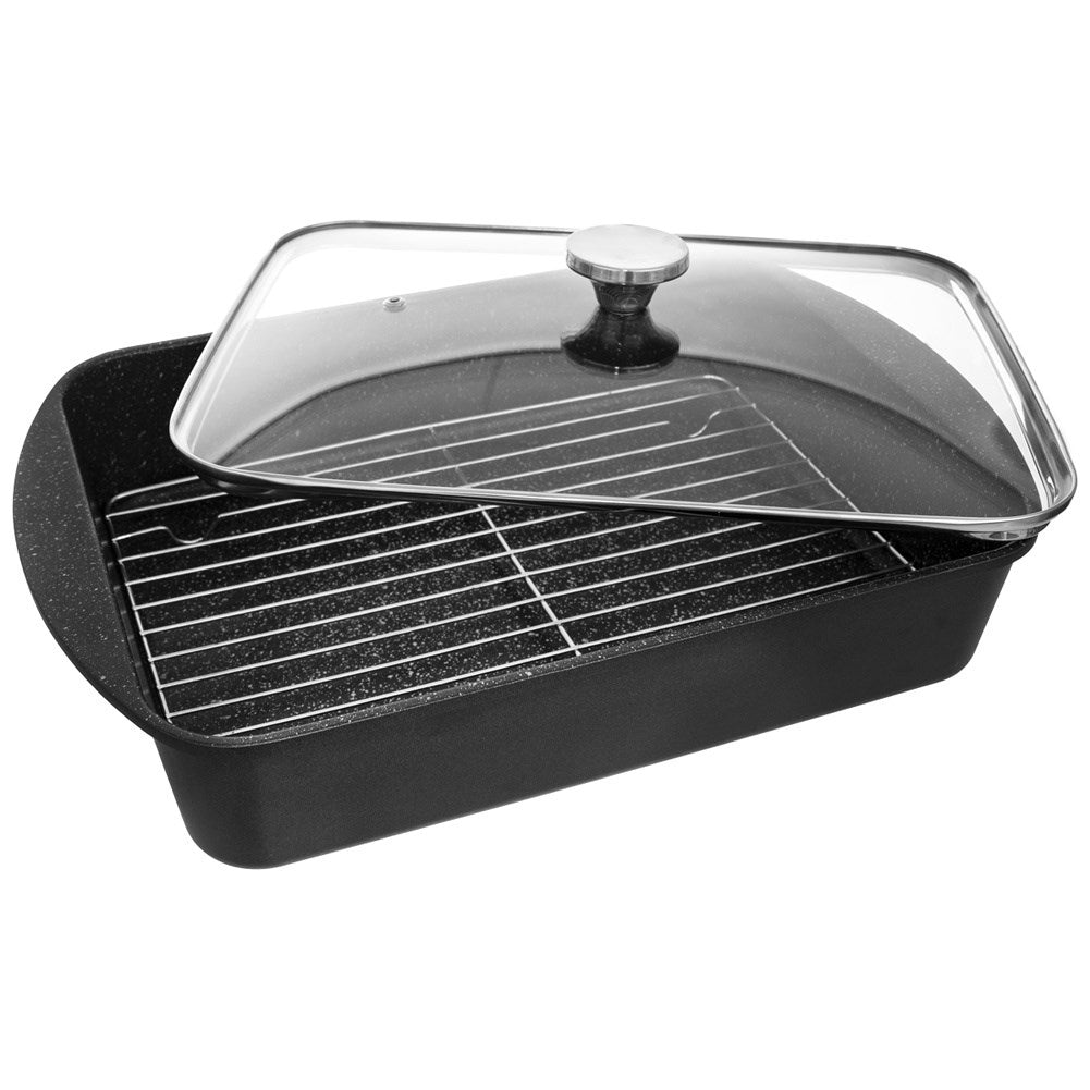 Fuente negra para asar con rejilla y tapa de cristal, sobre fondo blanco.