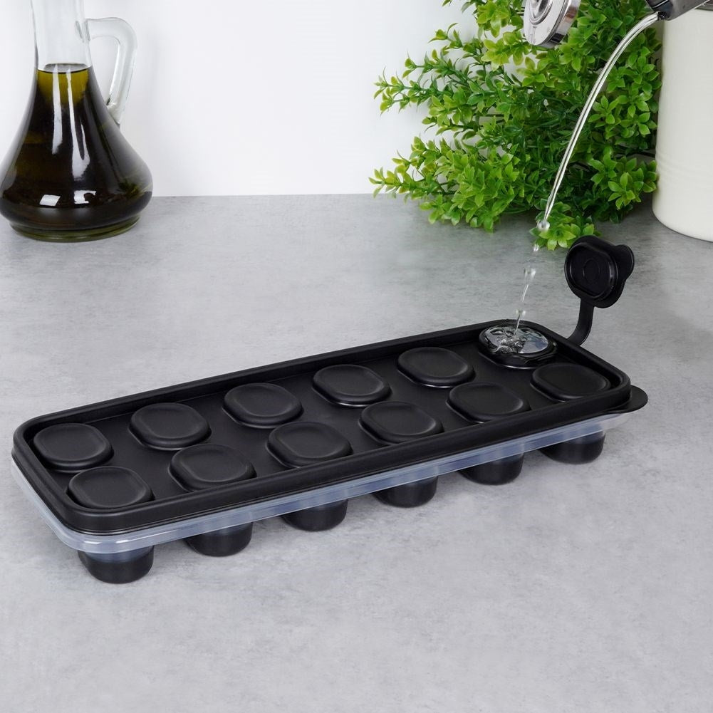 Una cubitera negra con 12 moldes redondos, que se está llenando de agua.