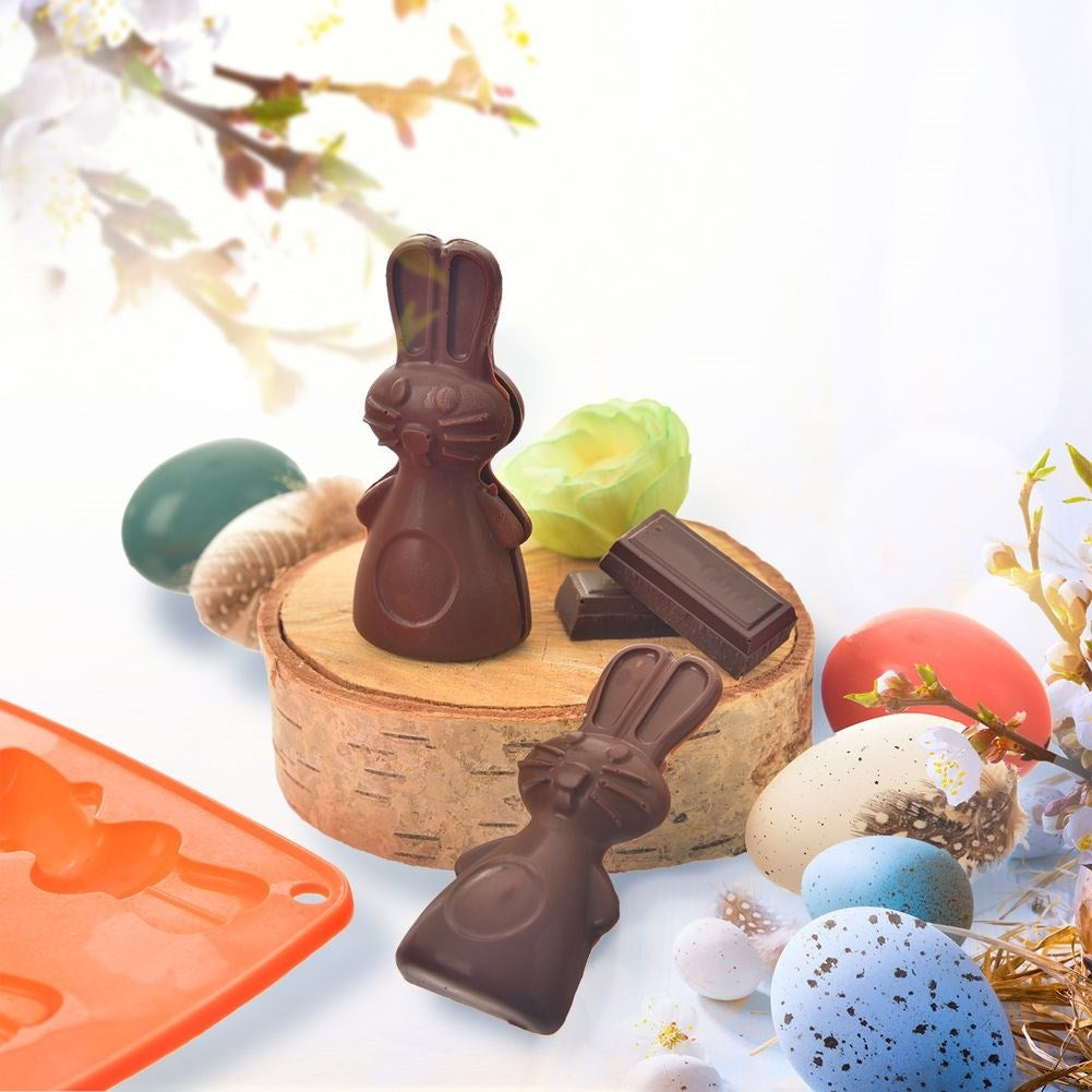 Conejos de chocolate, huevos, molde y flores sobre fondo claro.