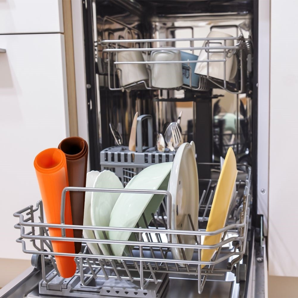 Lavavajillas abierto con platos en la rejilla inferior y tazas en la superior.
