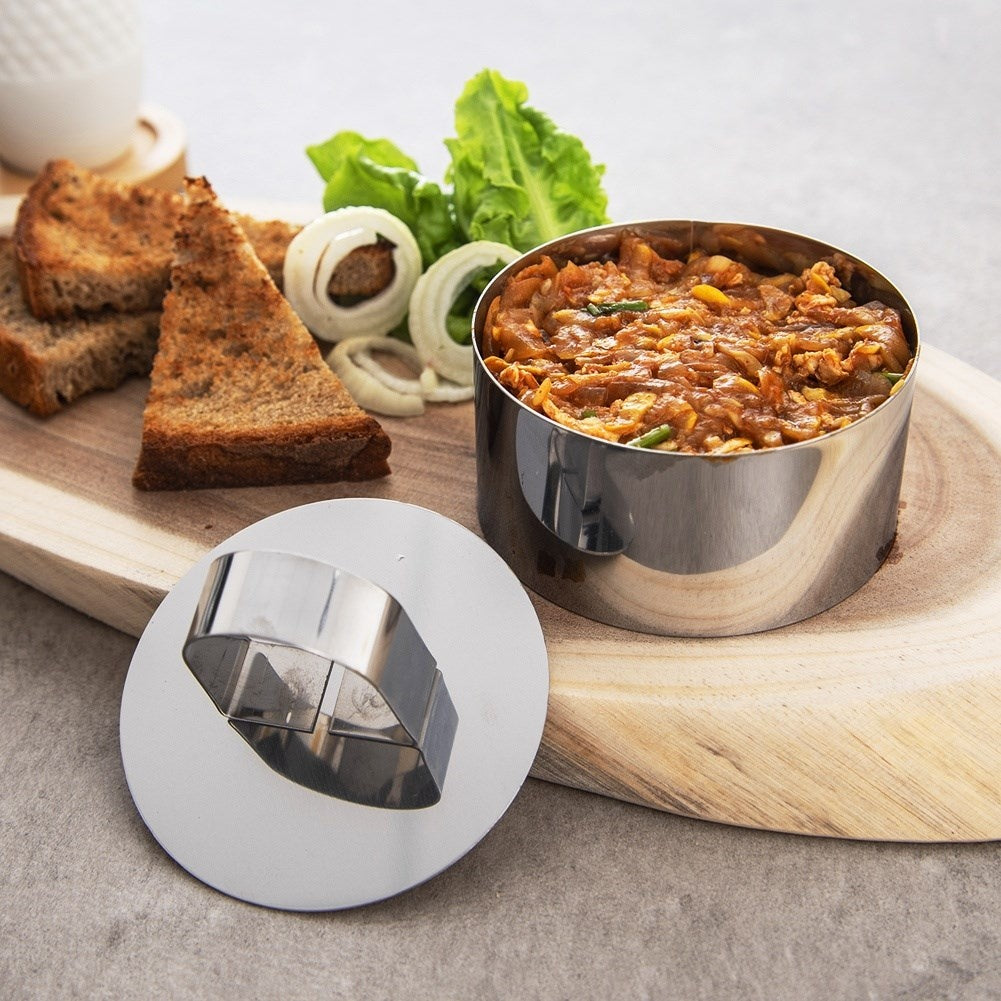 Un aro metálico contiene relleno de carne, junto a pan tostado y aros de cebolla.