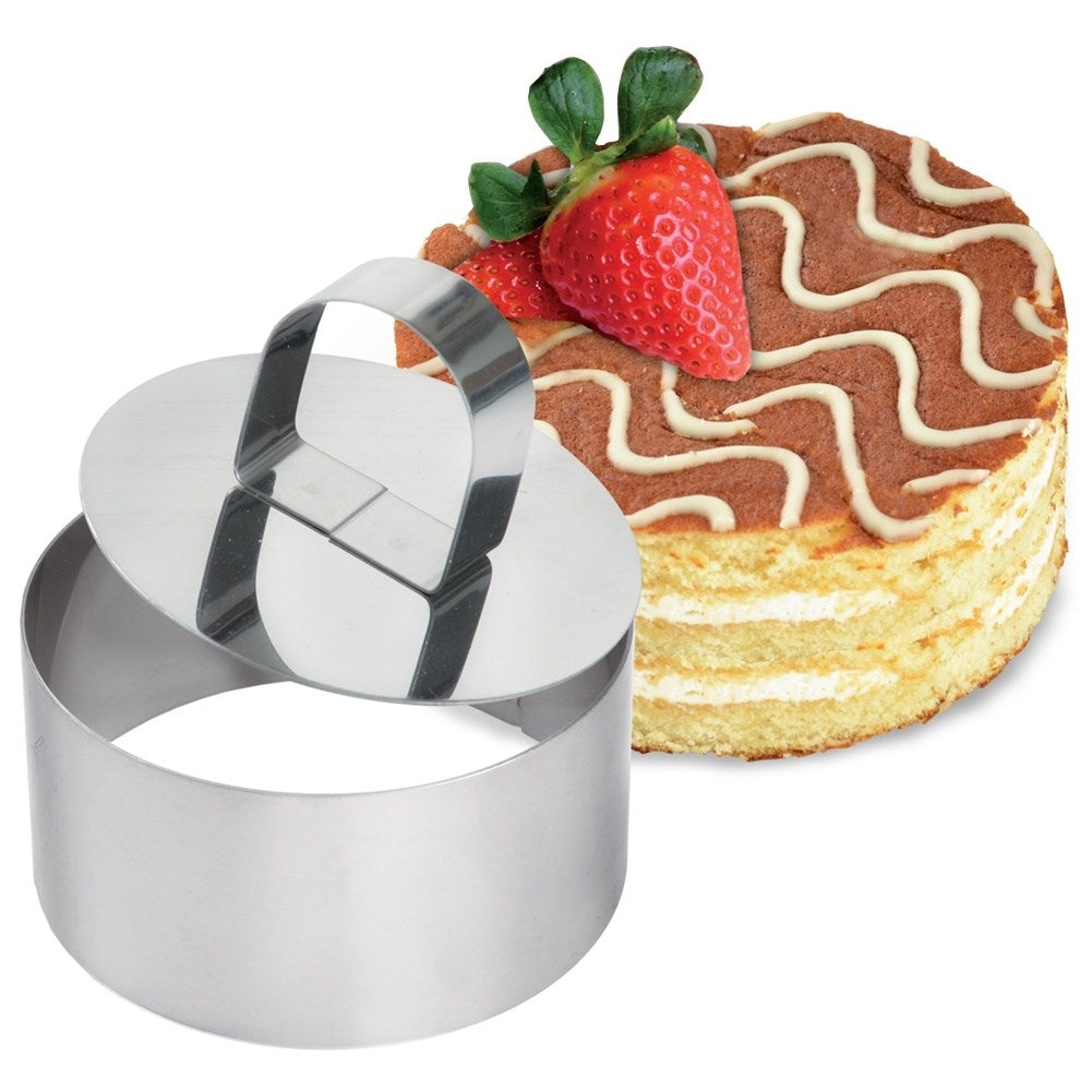 Un pastel redondo con crema blanca y glaseado de chocolate y un cortador de metal.