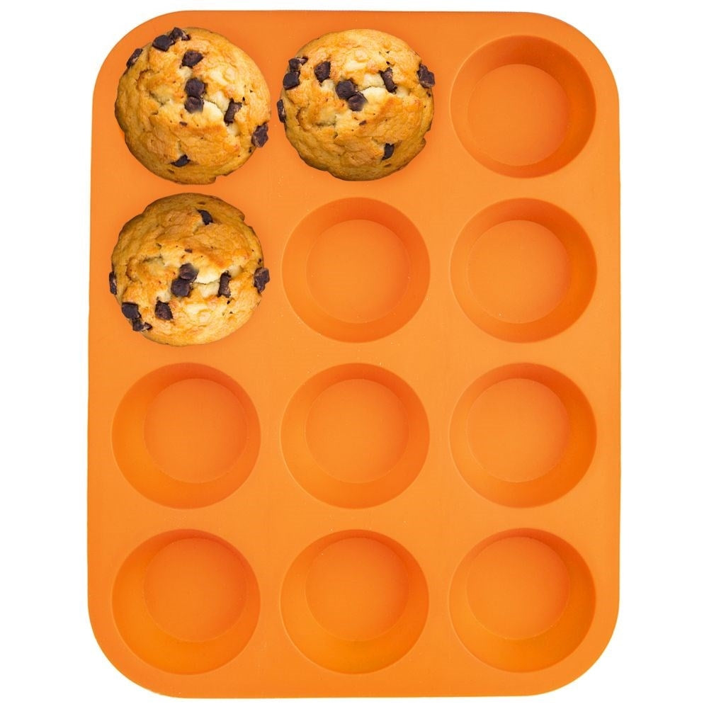 Tres muffins de chispas de chocolate en un molde de silicona naranja para 12.