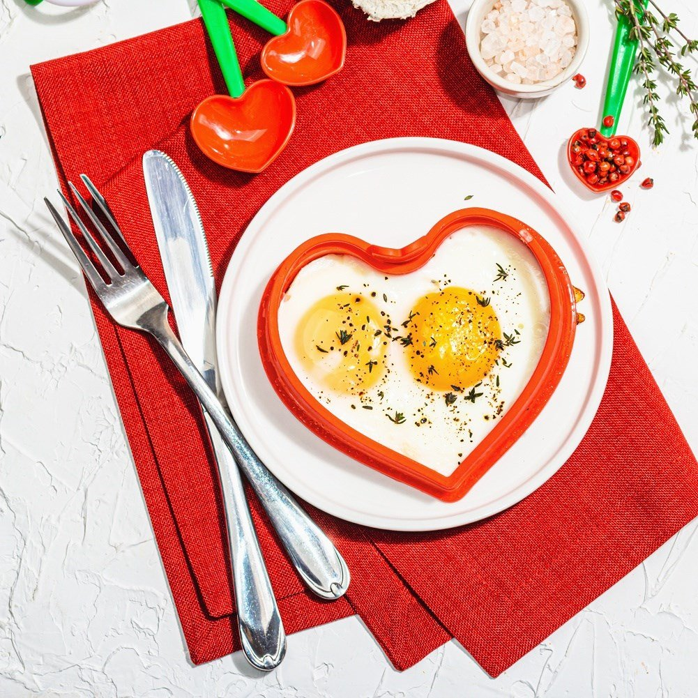 Dos huevos fritos con forma de corazón en un plato, espolvoreados.