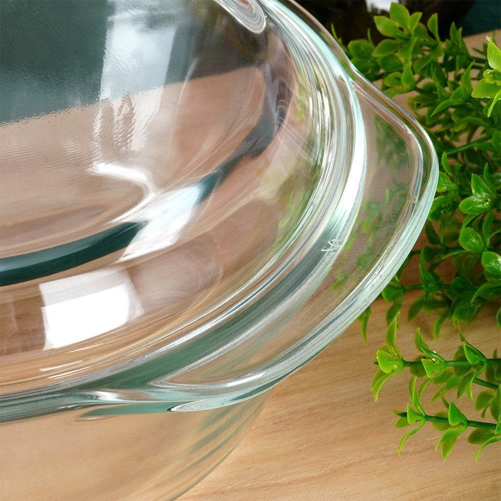 Una fuente de vidrio para cazuelas sobre una mesa de madera con plantas verdes.