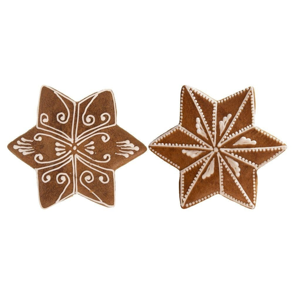 Dos galletas marrones en forma de estrella decoradas con glaseado blanco.