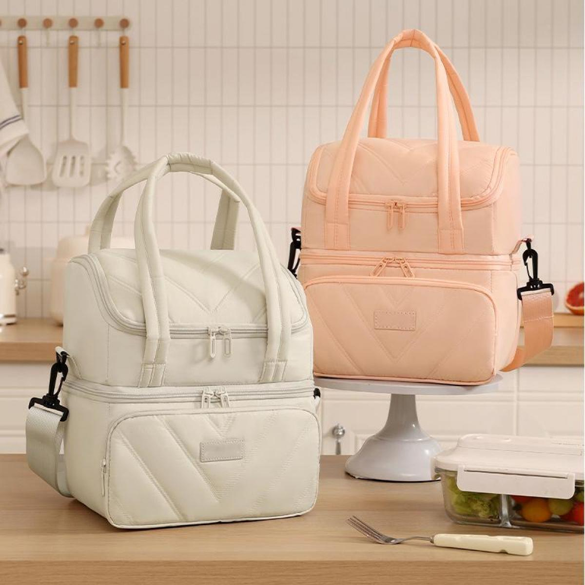 Zwei gesteppte Kühltaschen, eine weiße und eine pfirsichfarbene, auf einem Küchentisch.