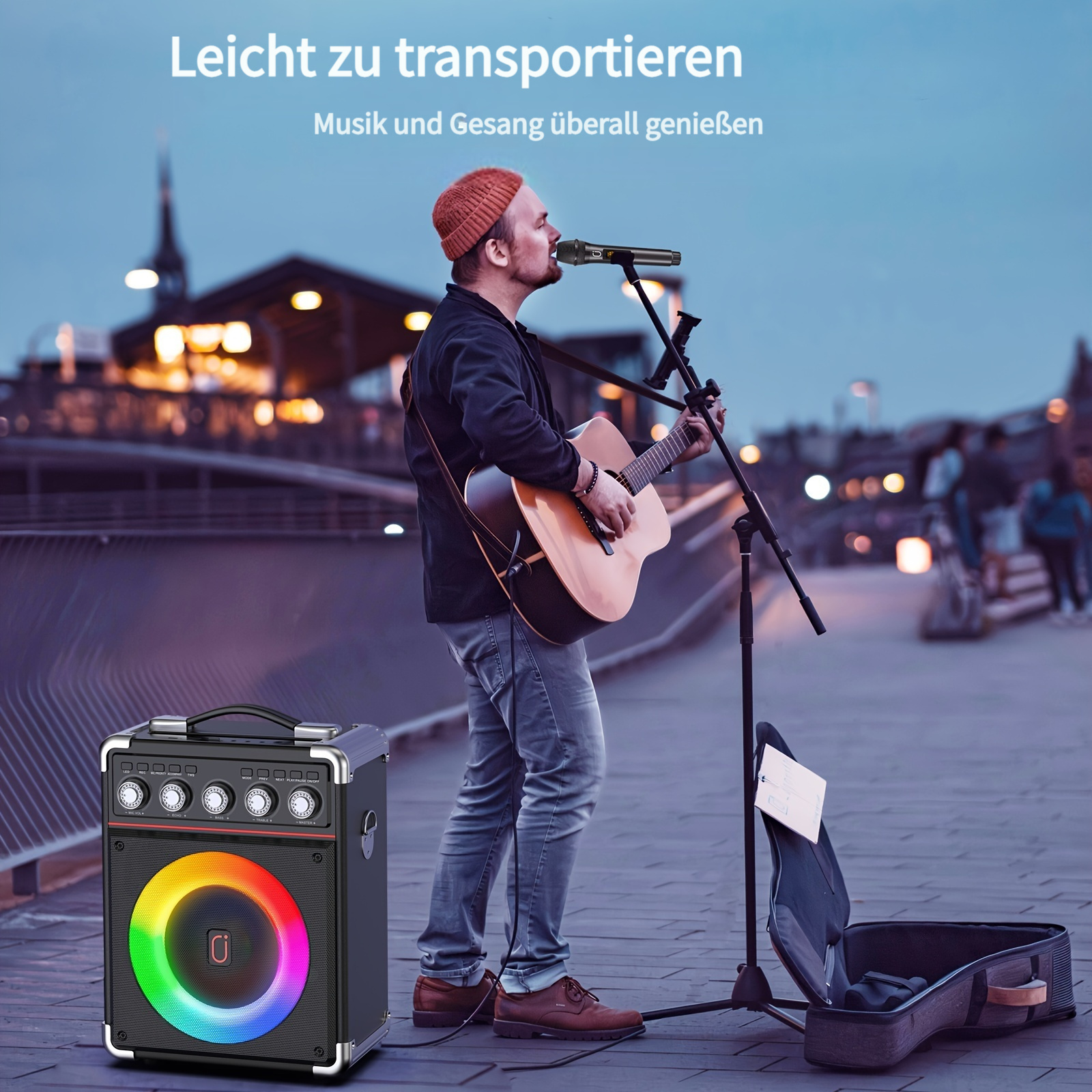 Mann spielt Gitarre und singt in ein Mikrofon. Lautsprecher mit Licht.