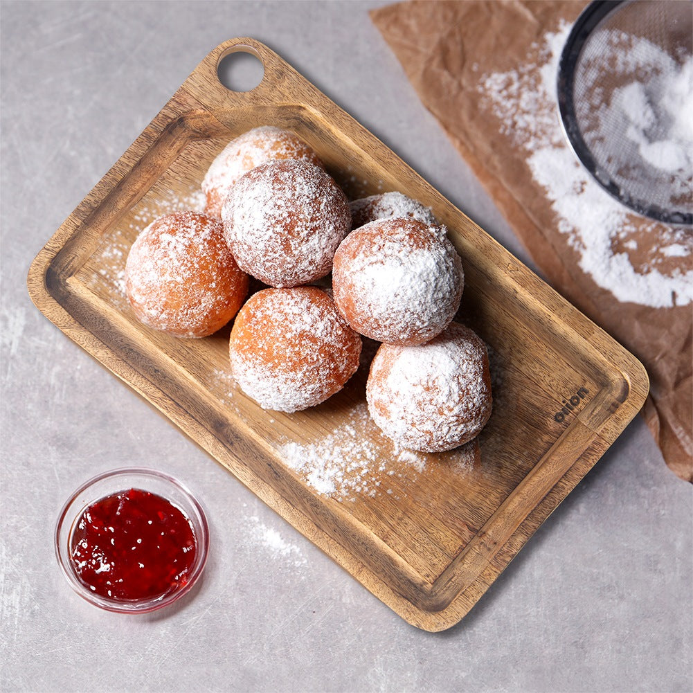 Donas cubiertas de azúcar glas sobre tabla de madera con mermelada.