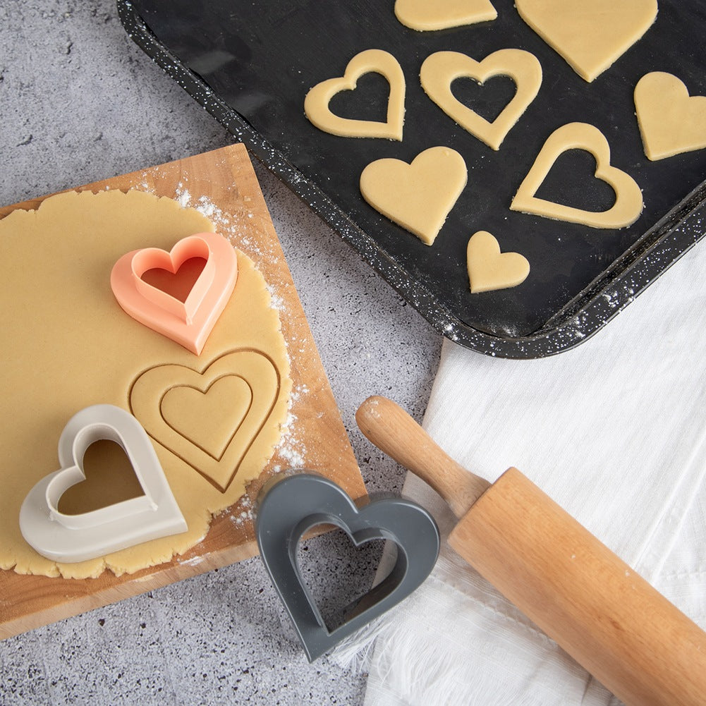 Galletas en forma de corazón se cortan de la masa con cortadores.