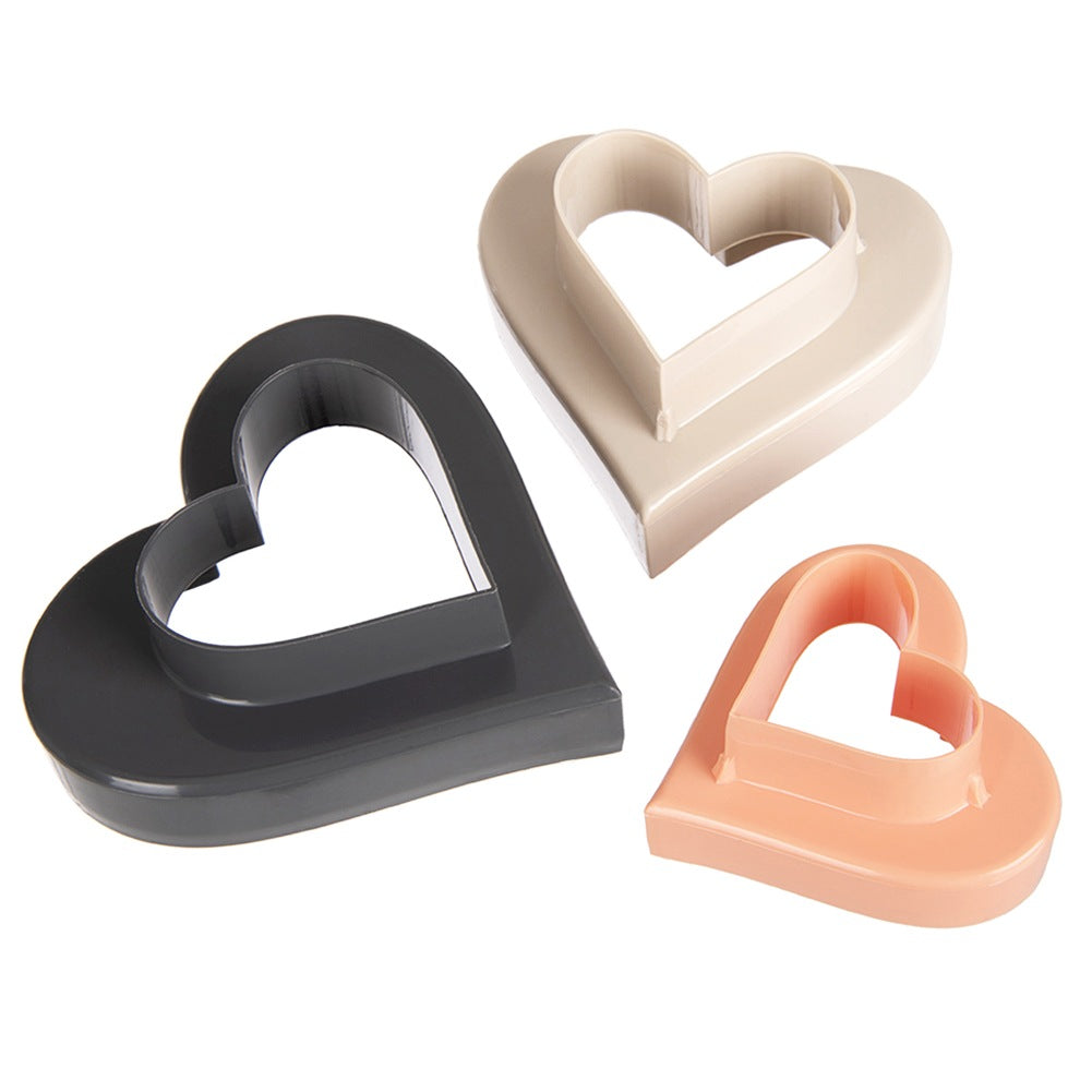 Tres cortadores de galletas en forma de corazón en gris, beige y melocotón.