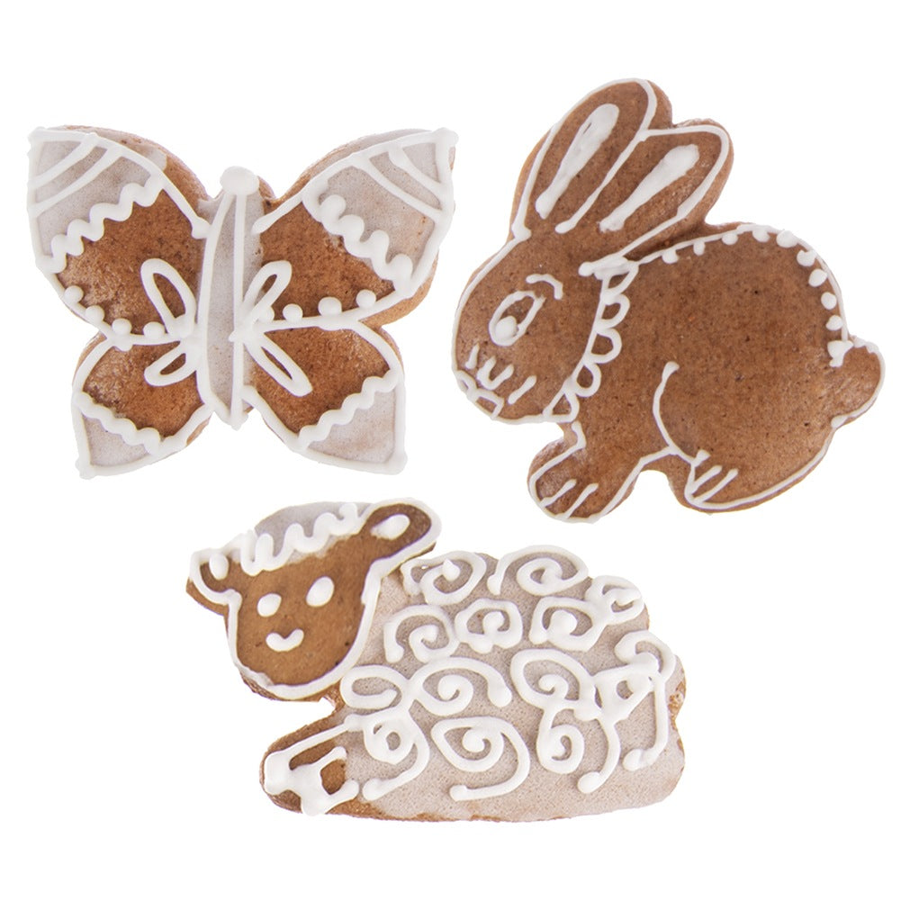 Galletas marrones de mariposa, conejo y oveja decoradas con glaseado blanco.