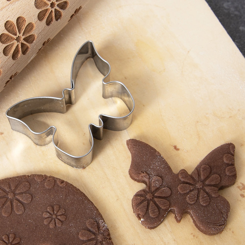 Un cortador de galletas con forma de mariposa junto a una galleta de mariposa.