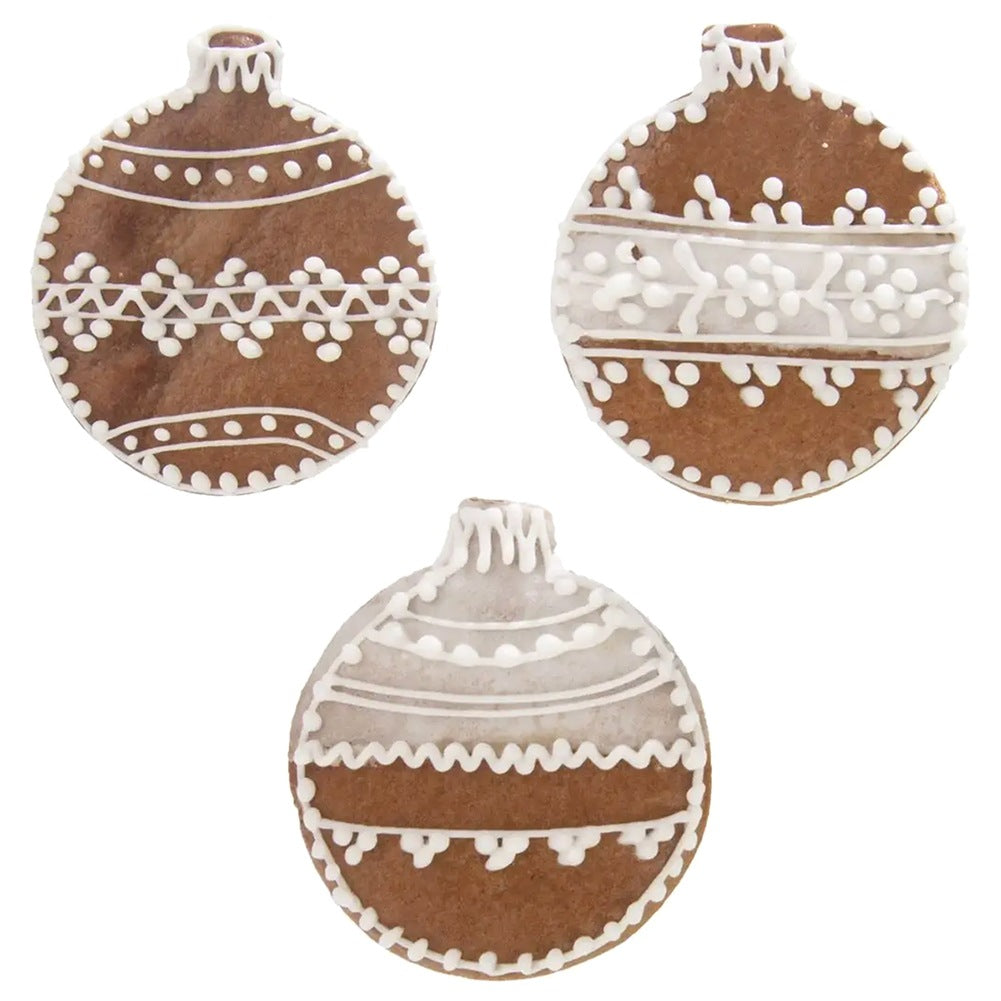 Tres galletas de jengibre marrones con forma de adornos navideños con decoraciones de glaseado blanco.