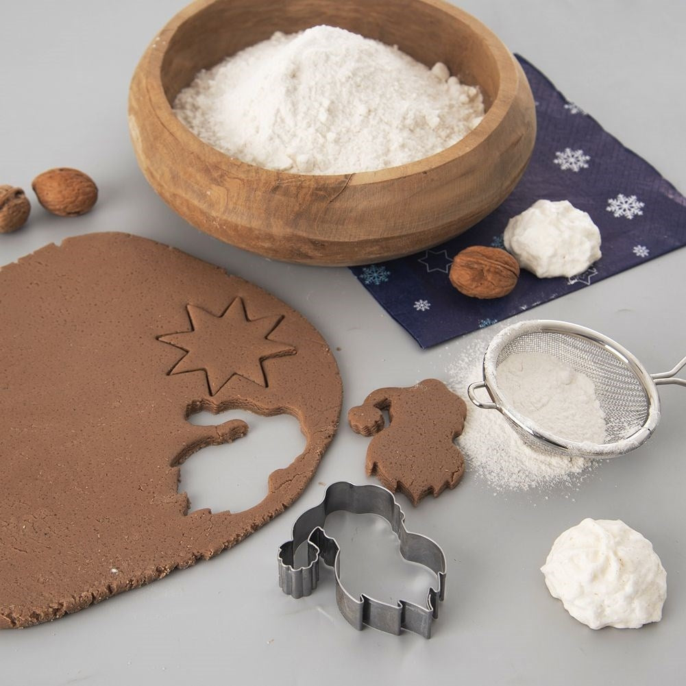 Masa marrón con cortador de estrella, nueces, harina en cuenco madera.