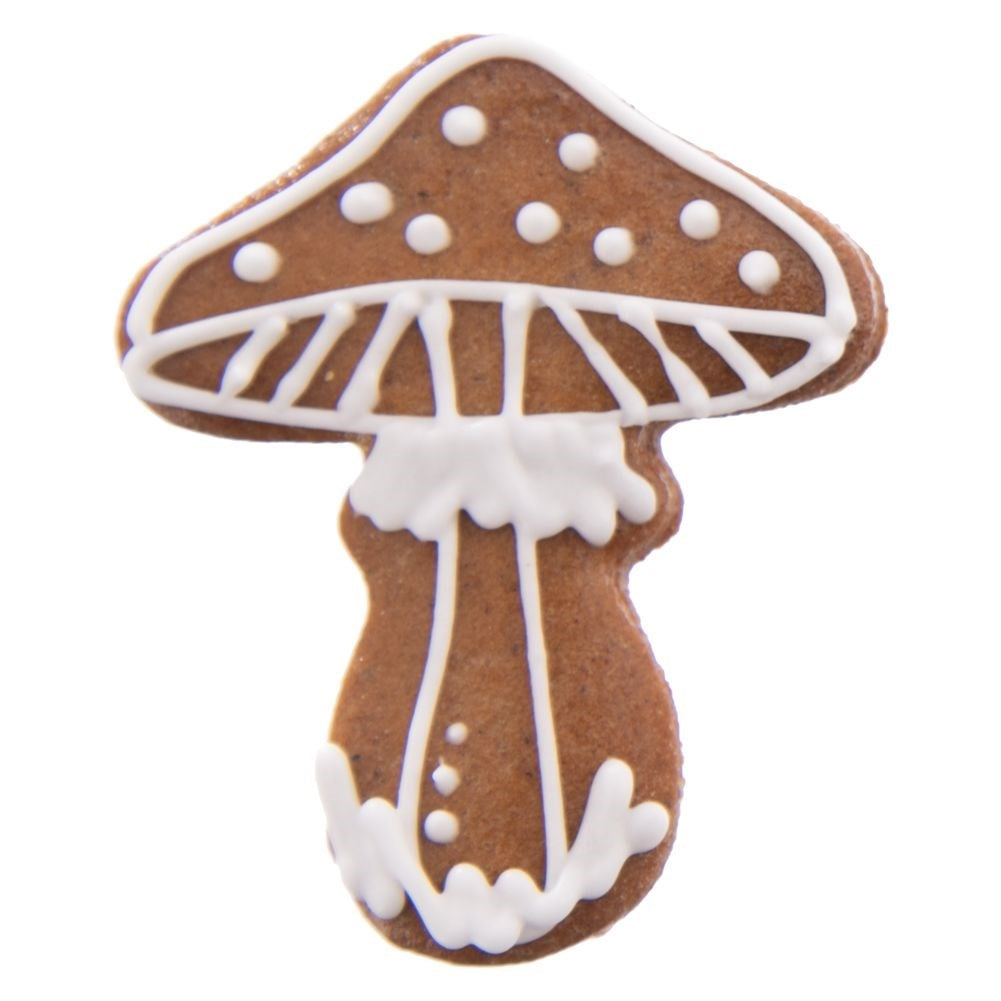 Una galleta marrón en forma de hongo decorada con glaseado blanco sobre fondo blanco.