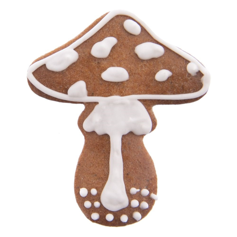 Una galleta marrón con forma de hongo decorada con glaseado blanco, sobre fondo blanco.