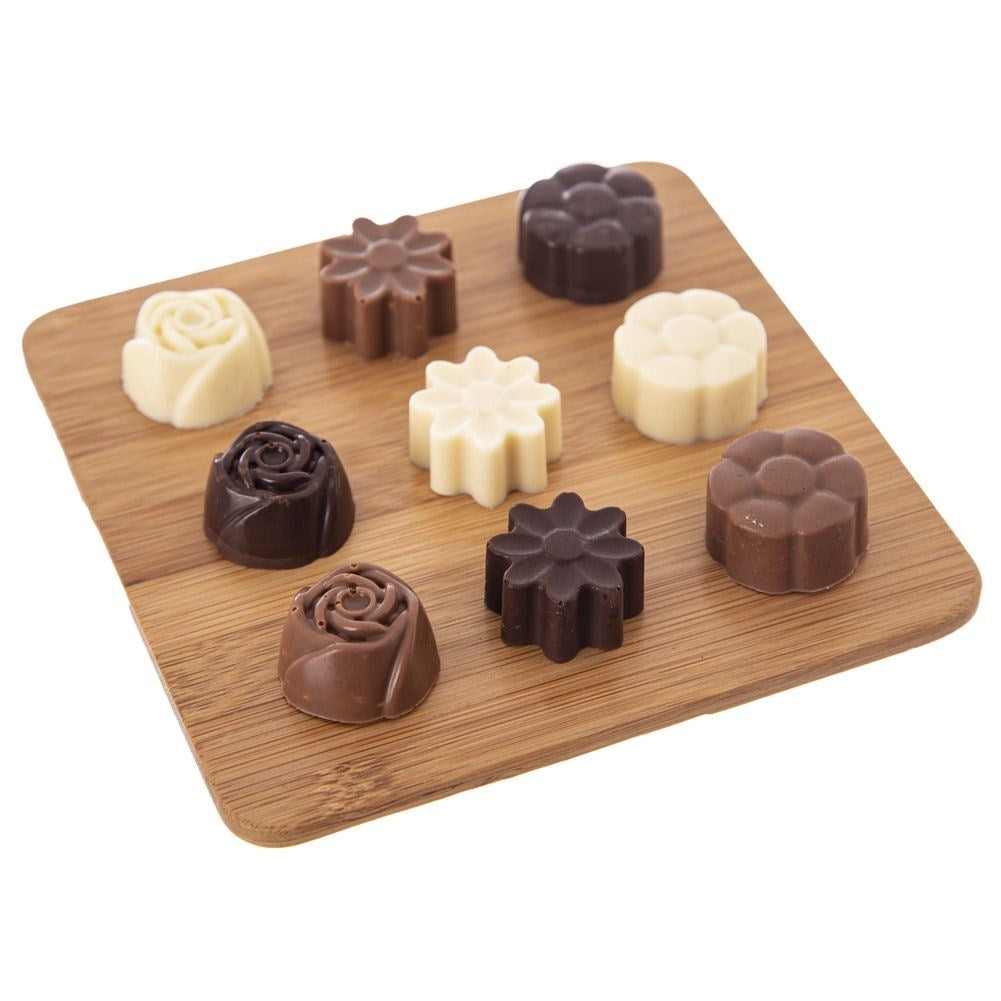 Una tabla de madera muestra ocho chocolates variados en forma de flor y rosa.