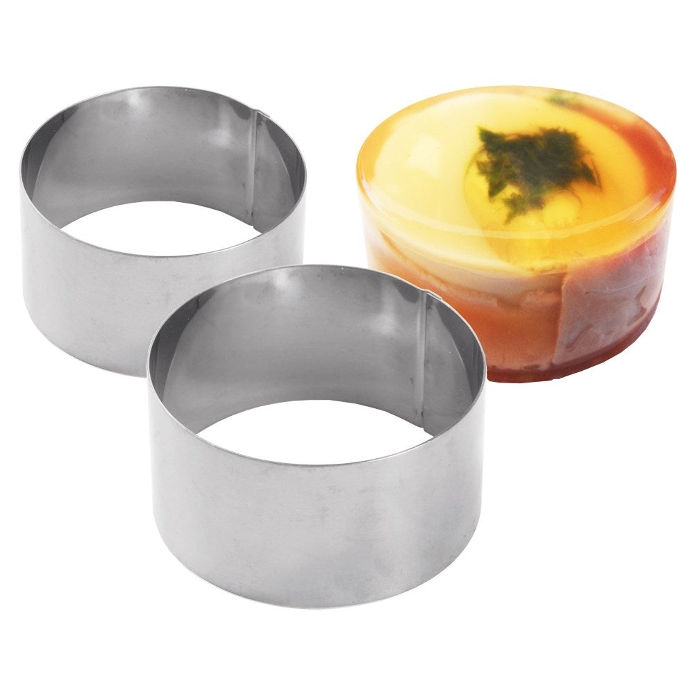 Dos moldes de anillo de acero inoxidable junto a un postre de gelatina en capas con hoja.