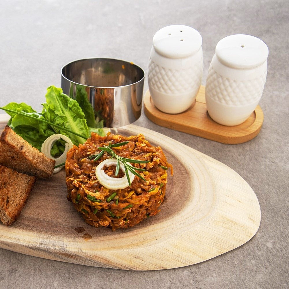 Tartar con tostada, ensalada y saleros en plato de madera.
